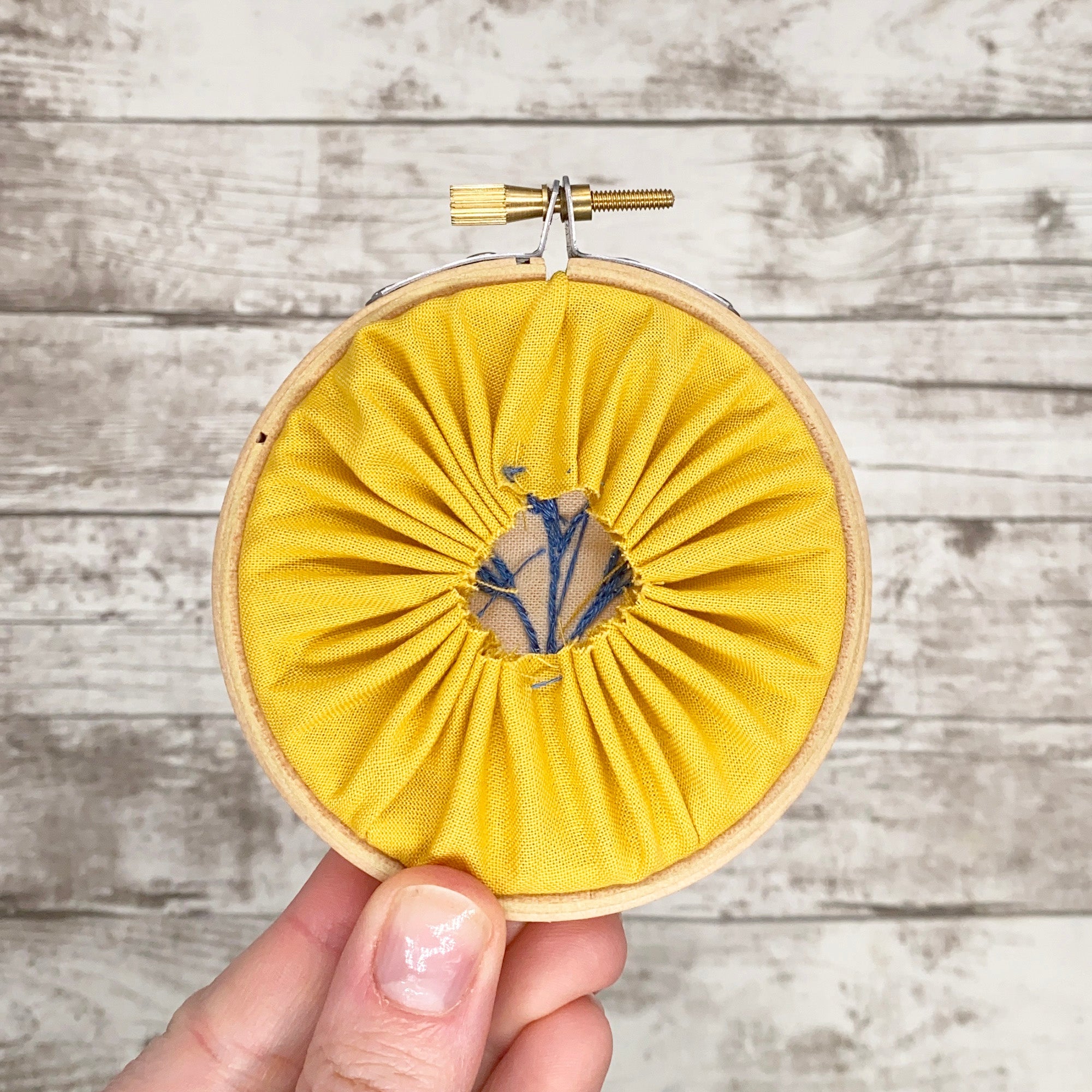 How to Back an Embroidery Hoop - yellow fabric gathered neatly behind an embroidery hoop