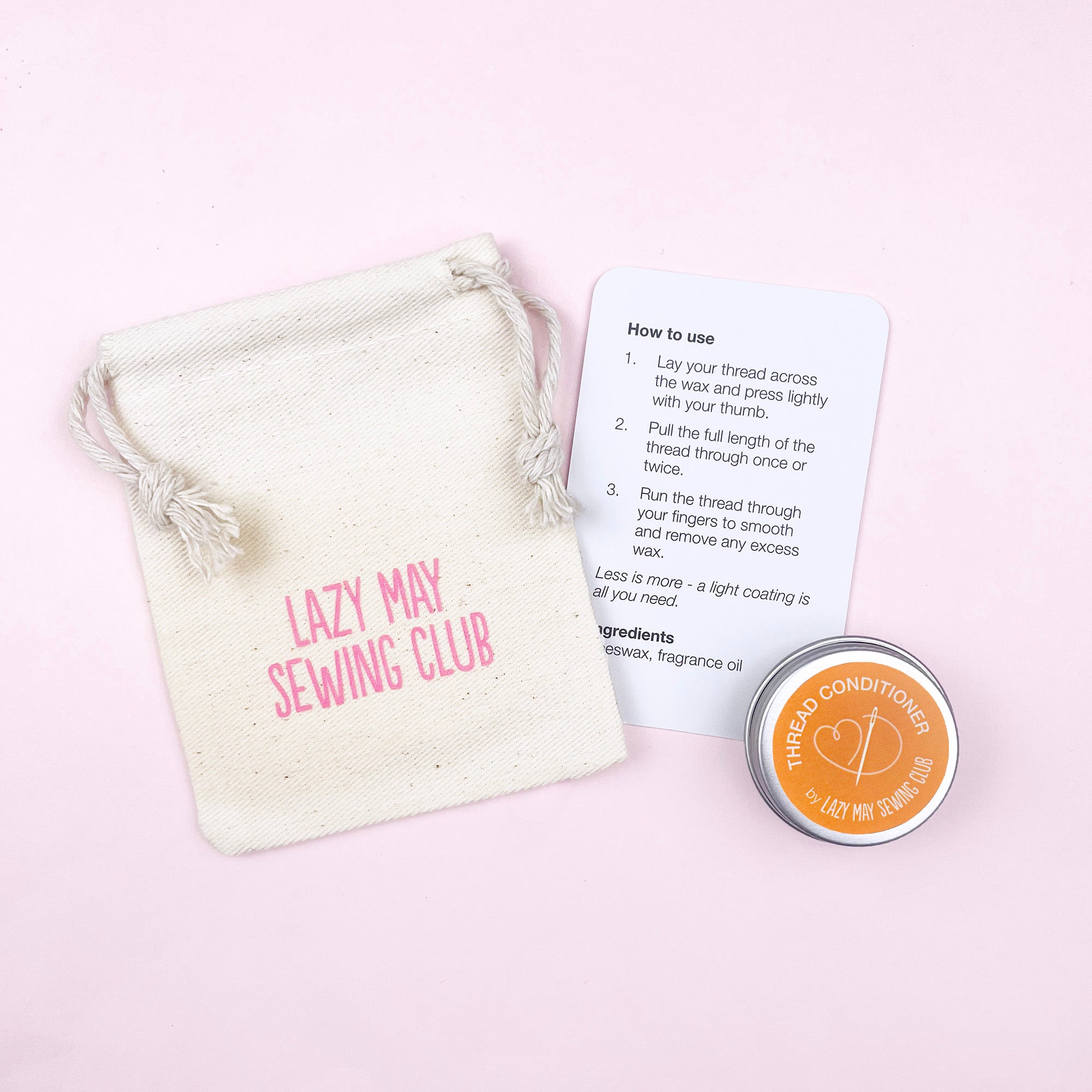 Lazy May Sewing Club product with a cotton pouch, card, and tin on a pink background
