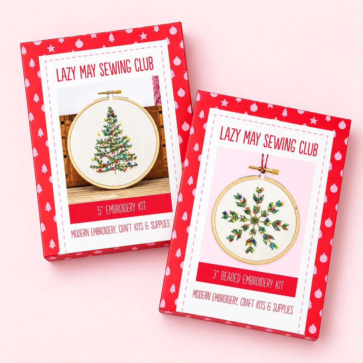 Two embroidery kits in red patterned boxes labeled 'Lazy May Sewing Club' on a light pink background. One box shows a 5" embroidery kit with a Christmas tree design, and the other shows a 3" beaded embroidery kit with a holly design.