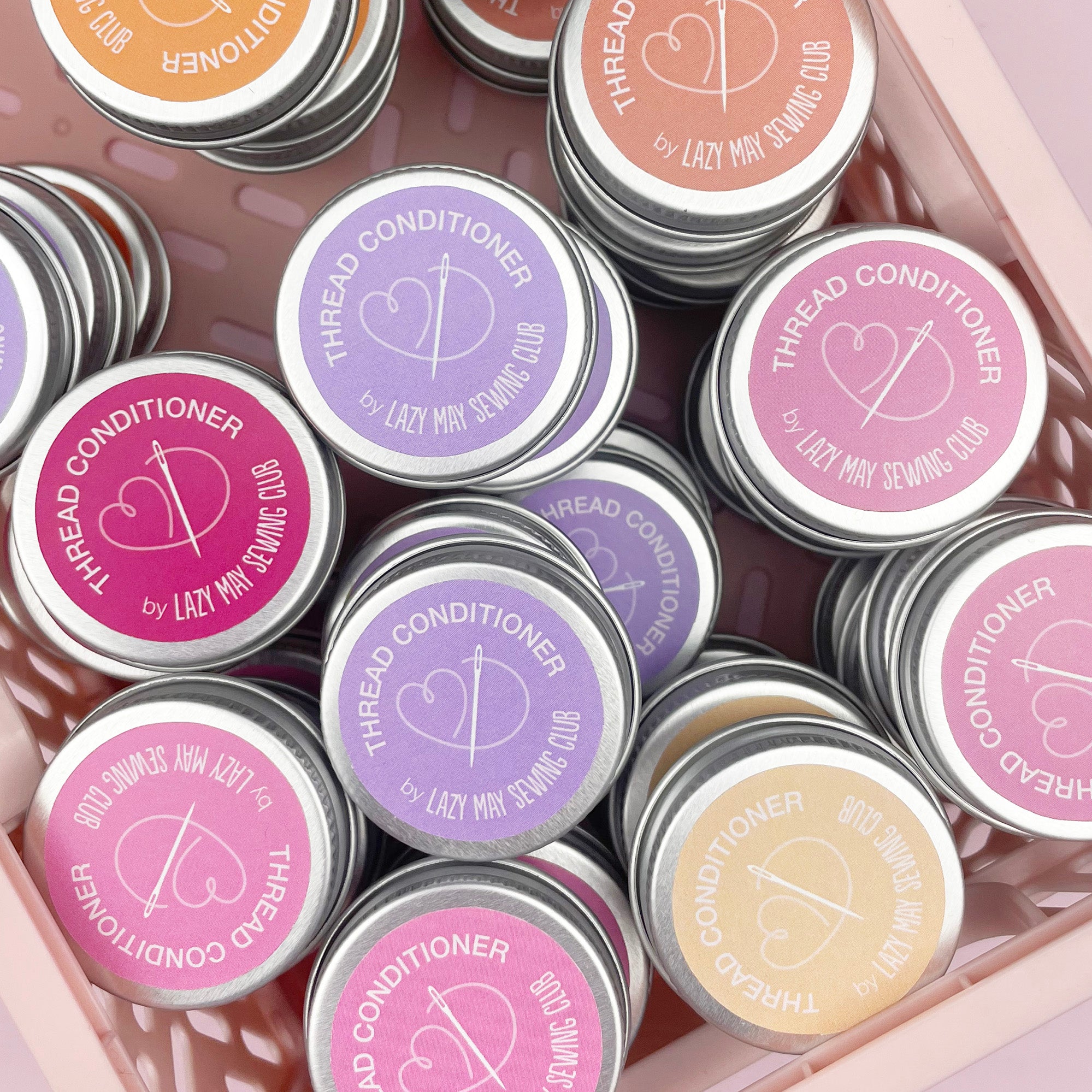 Multiple tins of 'Thread Conditioner' by Lazy May Sewing Club with colourful lids.