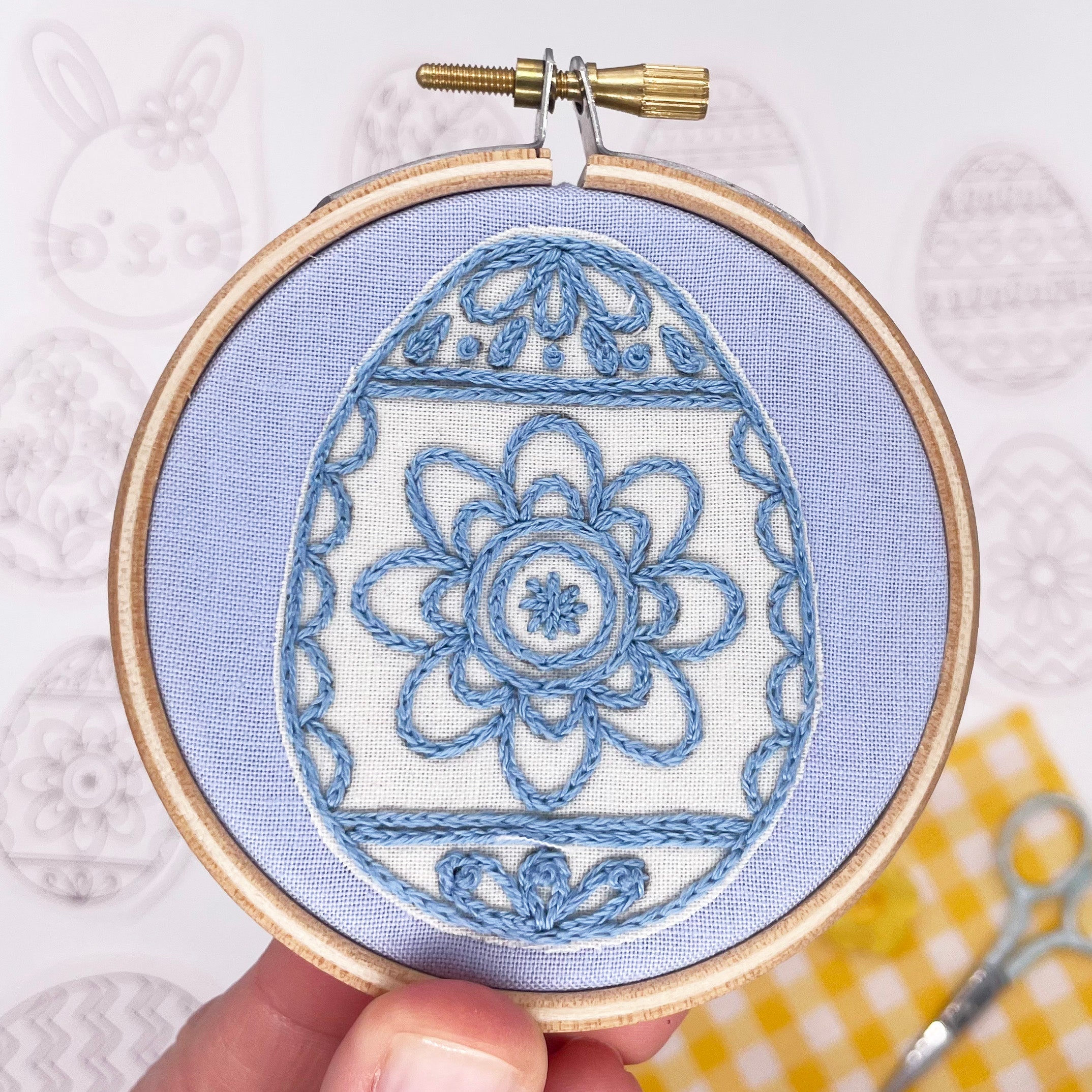 Completed Easter embroidery design featuring a blue floral Easter egg stitched on fabric in an embroidery hoop. A great Easter craft idea for stitchers of all levels.