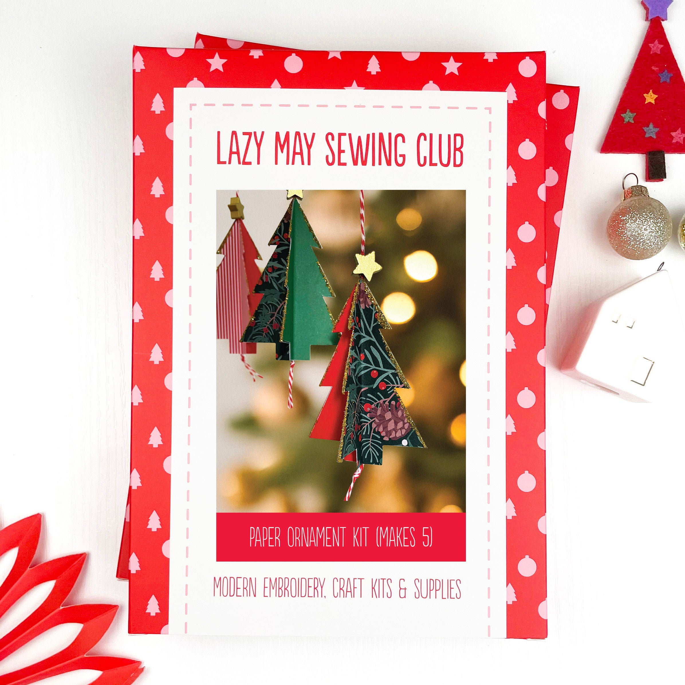 Lazy May Sewing Club paper ornament kit packaging with Christmas tree decorations on a white background.