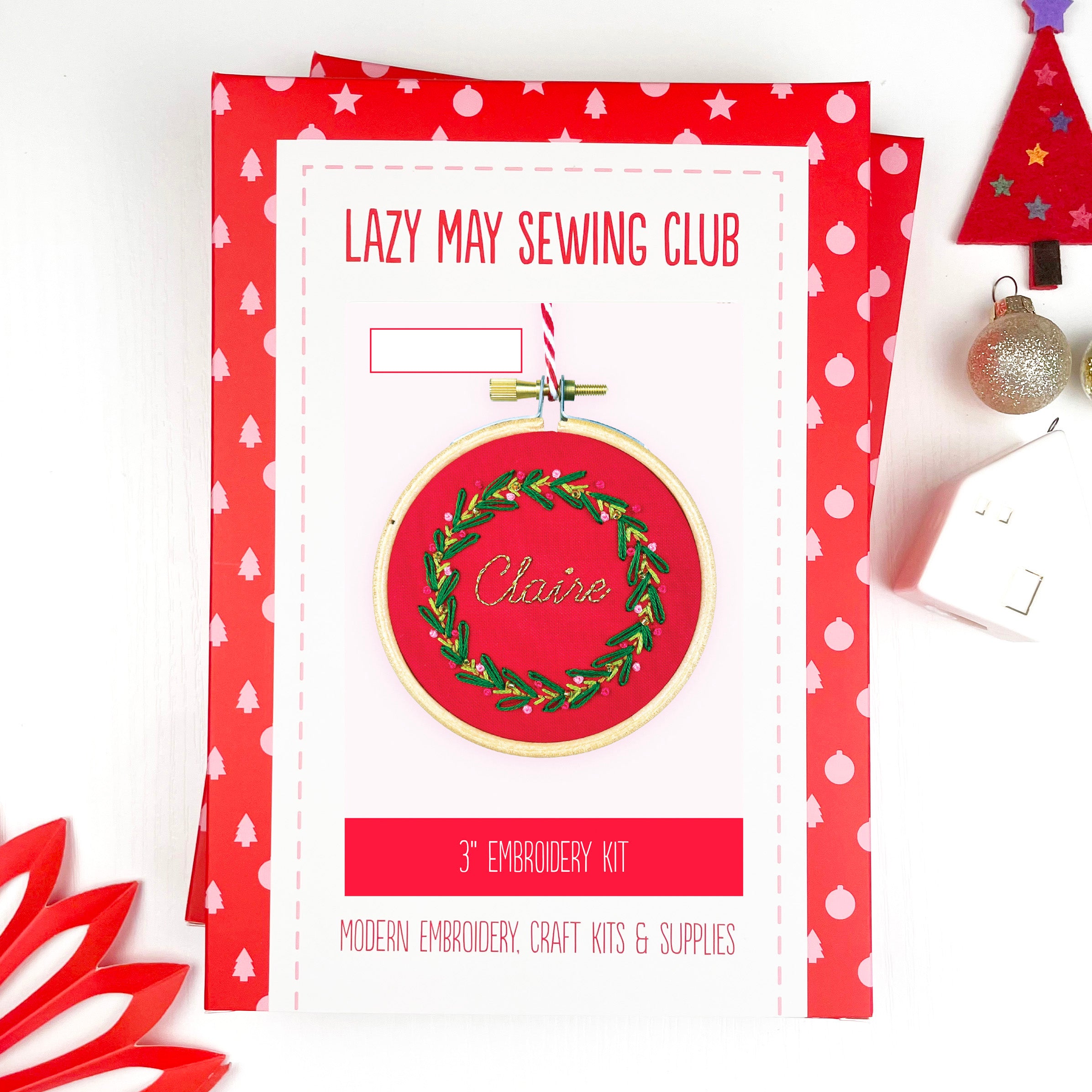 Embroidery kit packaging for Lazy May Sewing Club with wreath design and text.