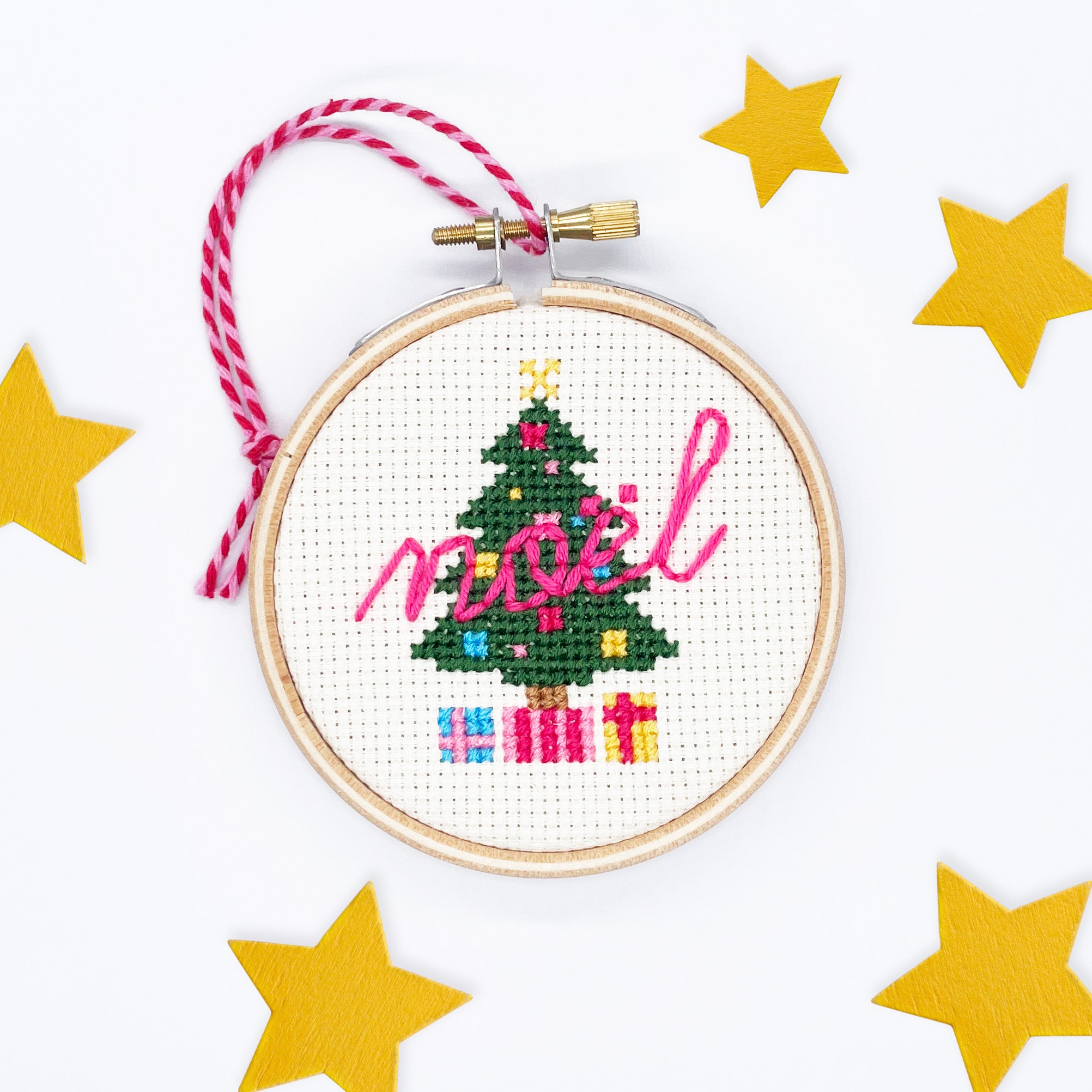 Christmas Tree: Cross Stitch Kit with stitched green tree, colorful presents, and pink "noel" text in wooden hoop ornament