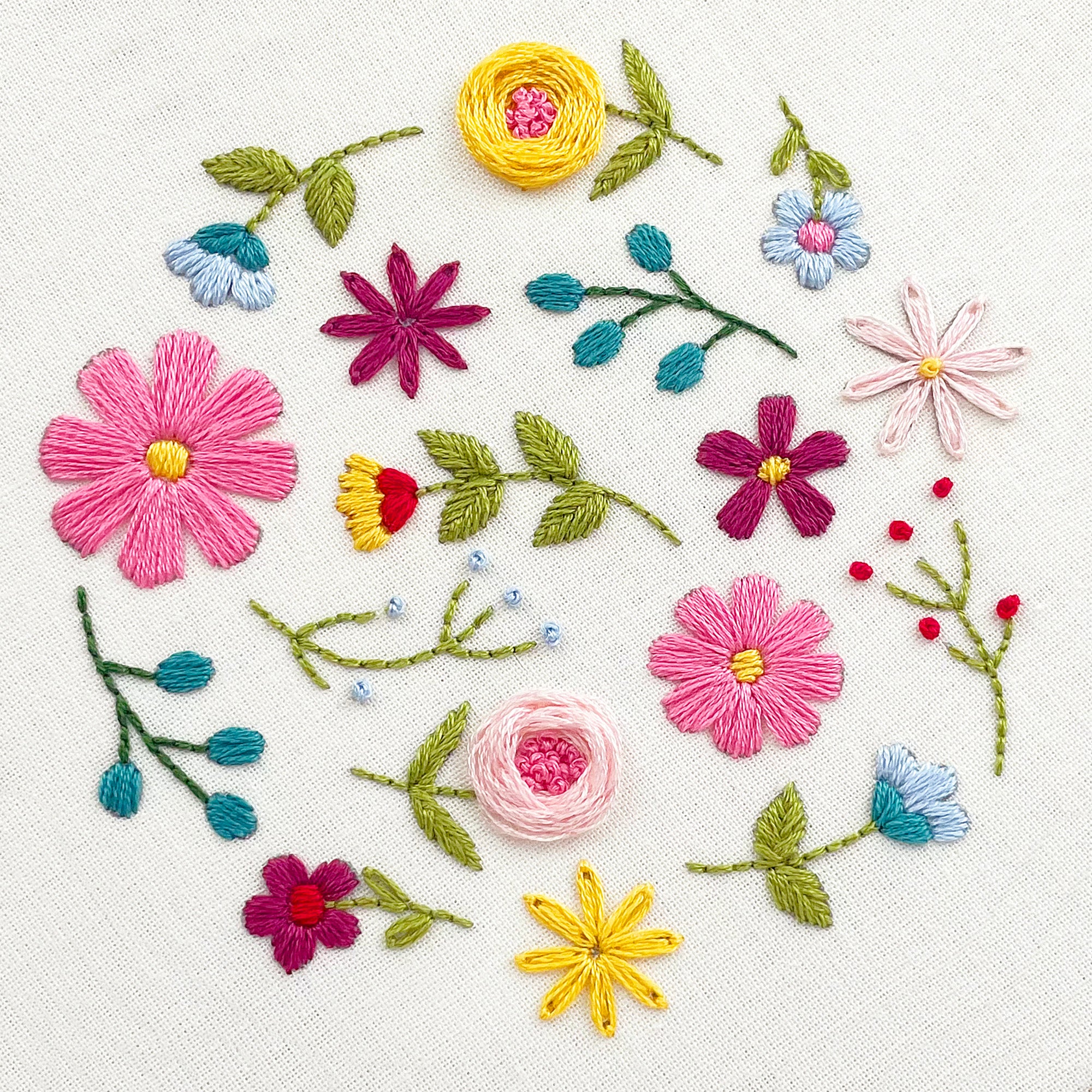 Close-up of colourful stitching showing finished floral embroidery pattern with pink, yellow and blue wildflowers.