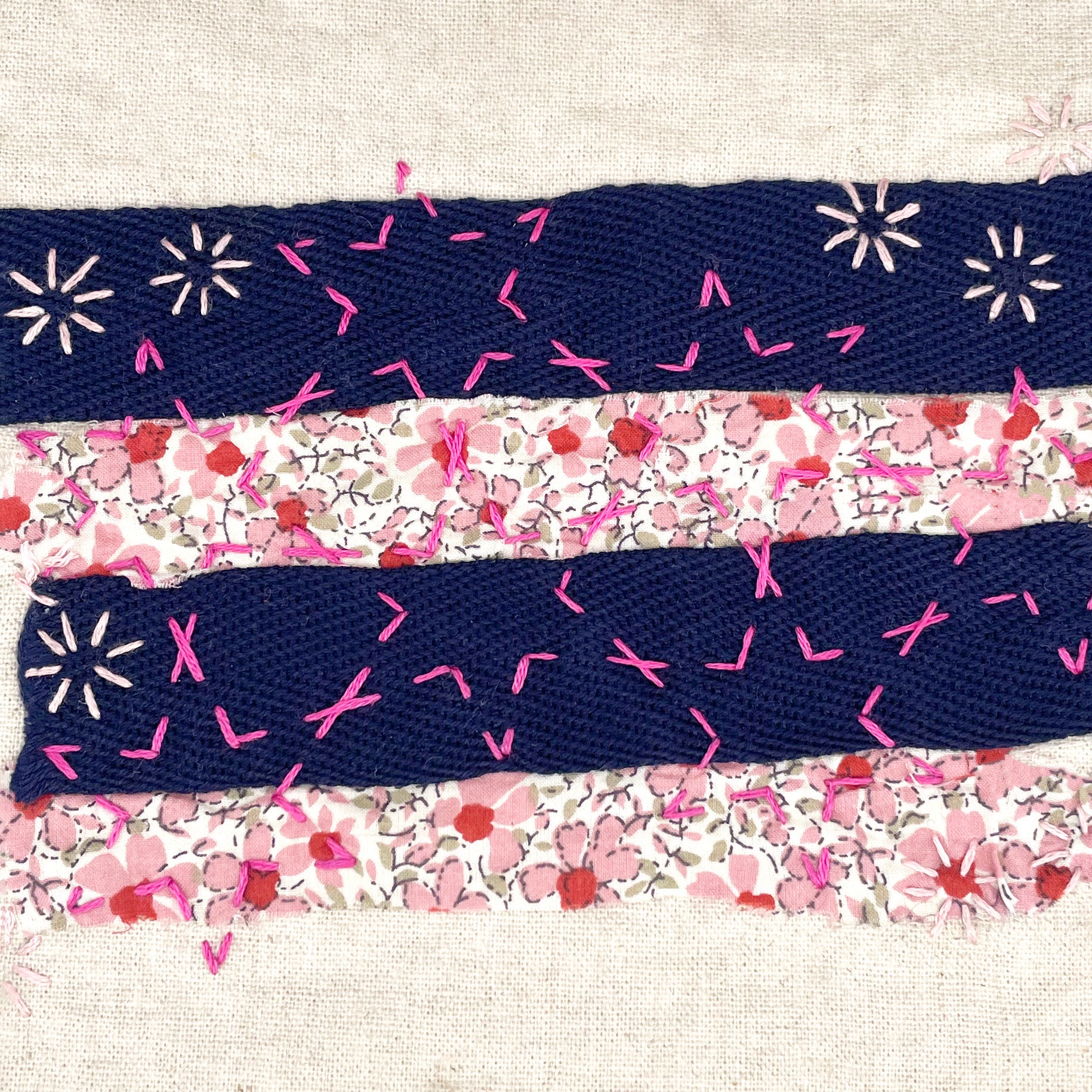 Close-up of hand-stitched fabric piece with pink embroidery patterns from Visible Mending Kit: Sashiko Inspired Stick and Stitch Patterns