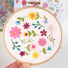 Hand holding finished floral embroidery hoop with bold wildflower design – DIY embroidery craft kit for adults.