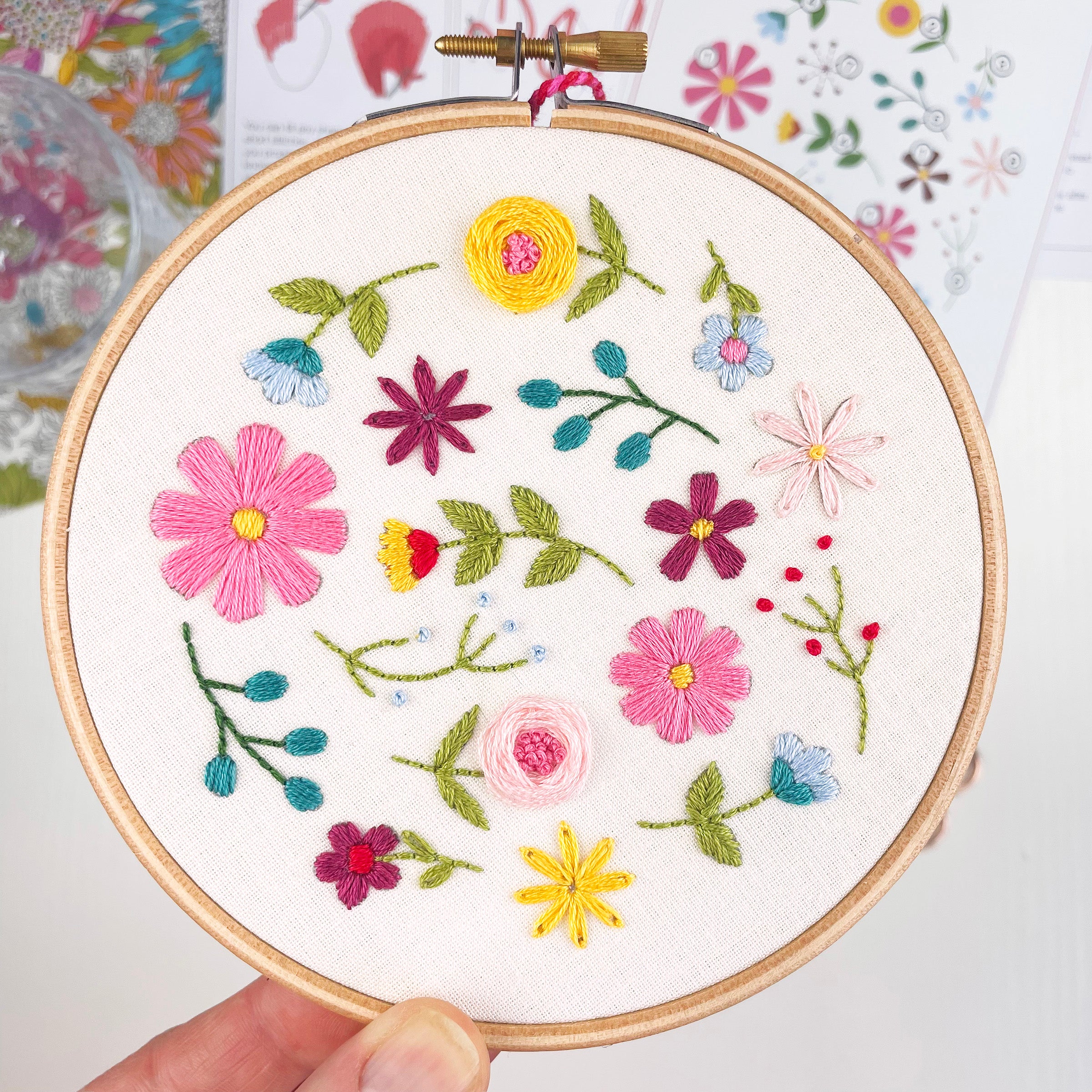 Hand holding finished floral embroidery hoop with bold wildflower design – DIY embroidery craft kit for adults.