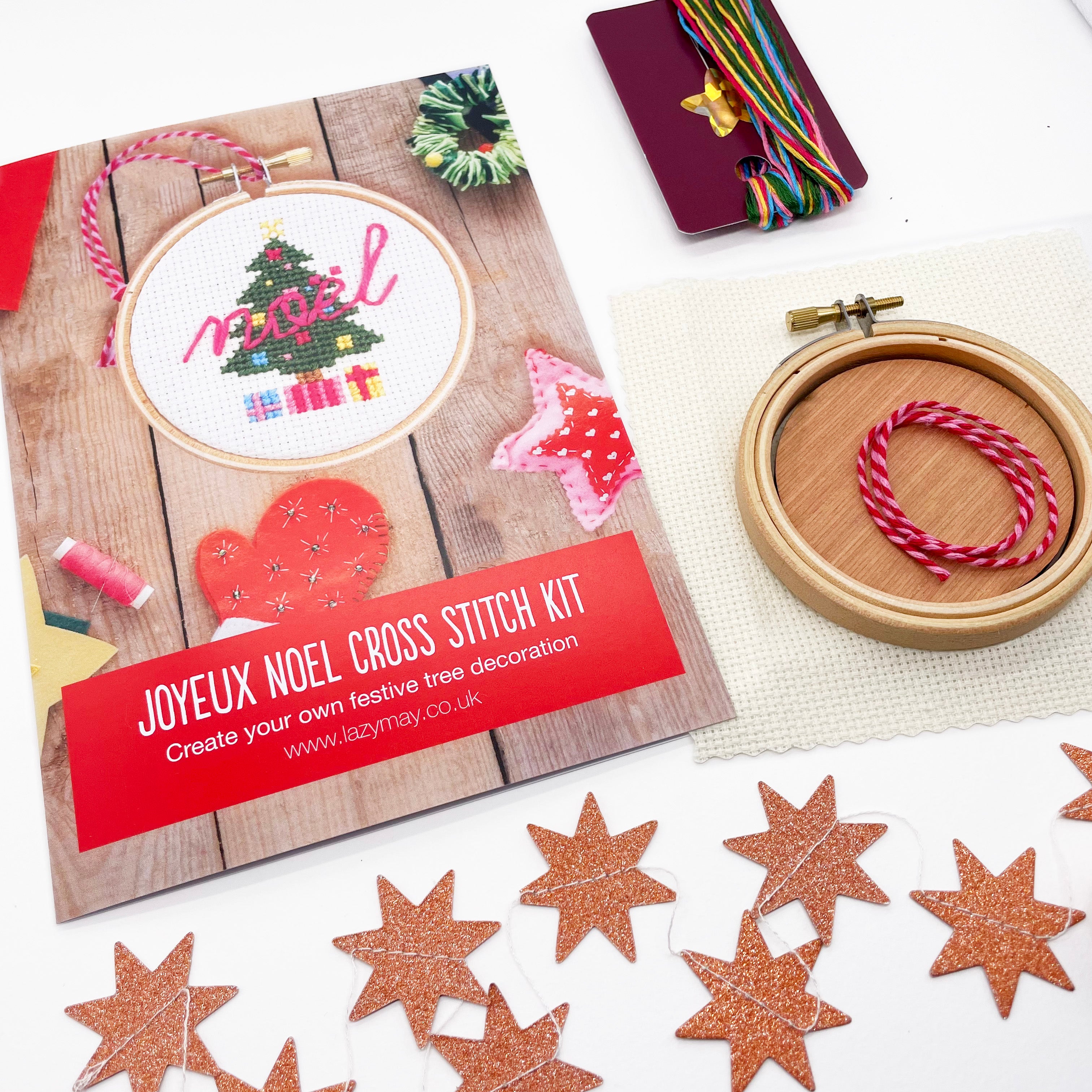 Christmas Tree: Cross Stitch Kit with colorful threads, hoop, and festive star-shaped decorations on a white background