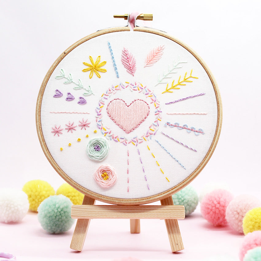 Embroidery Kit: 5" Beginners Stitch Sampler with colorful stitches and heart design displayed on wooden hoop and stand