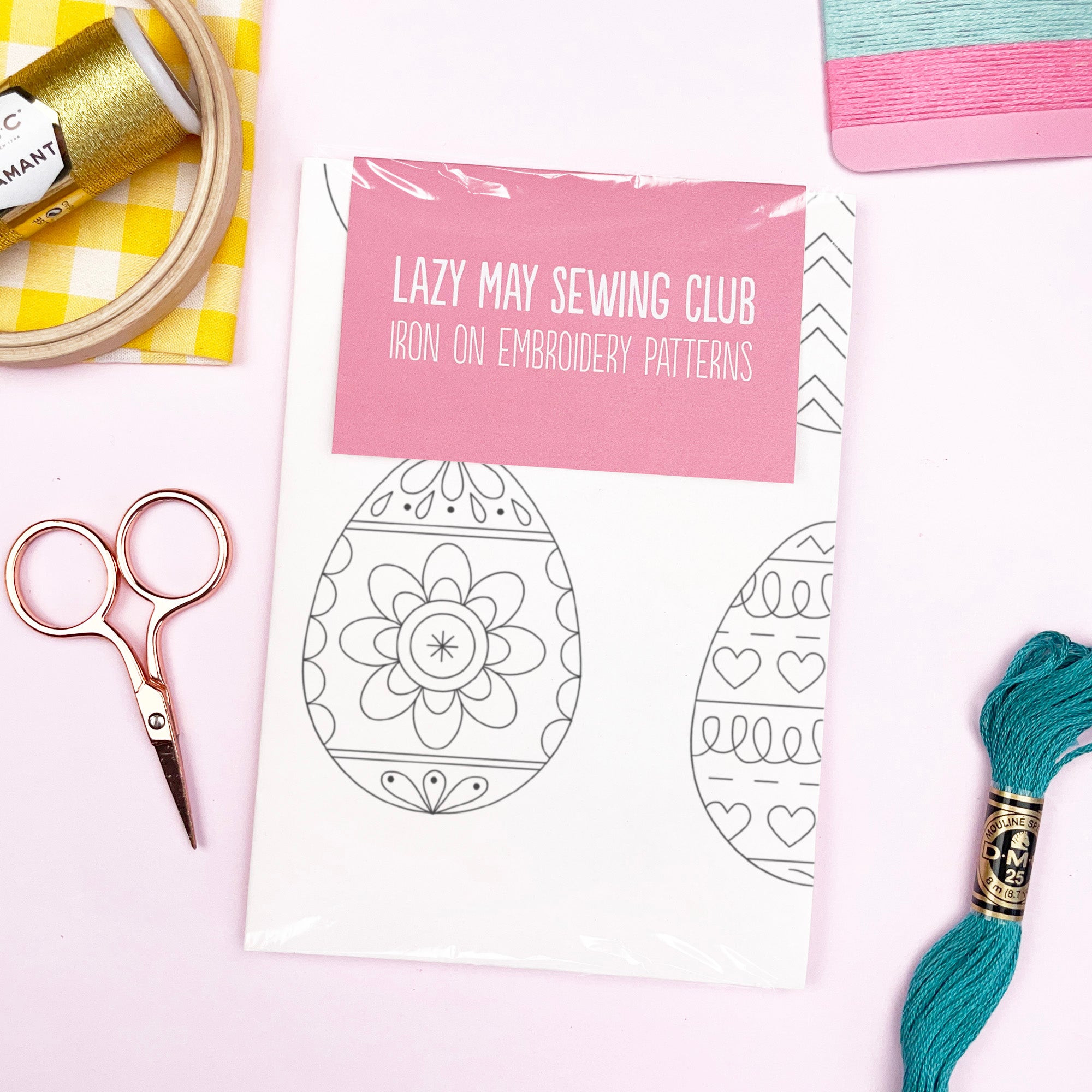 Iron on embroidery patterns from Lazy May Sewing Club with sewing tools on a white background