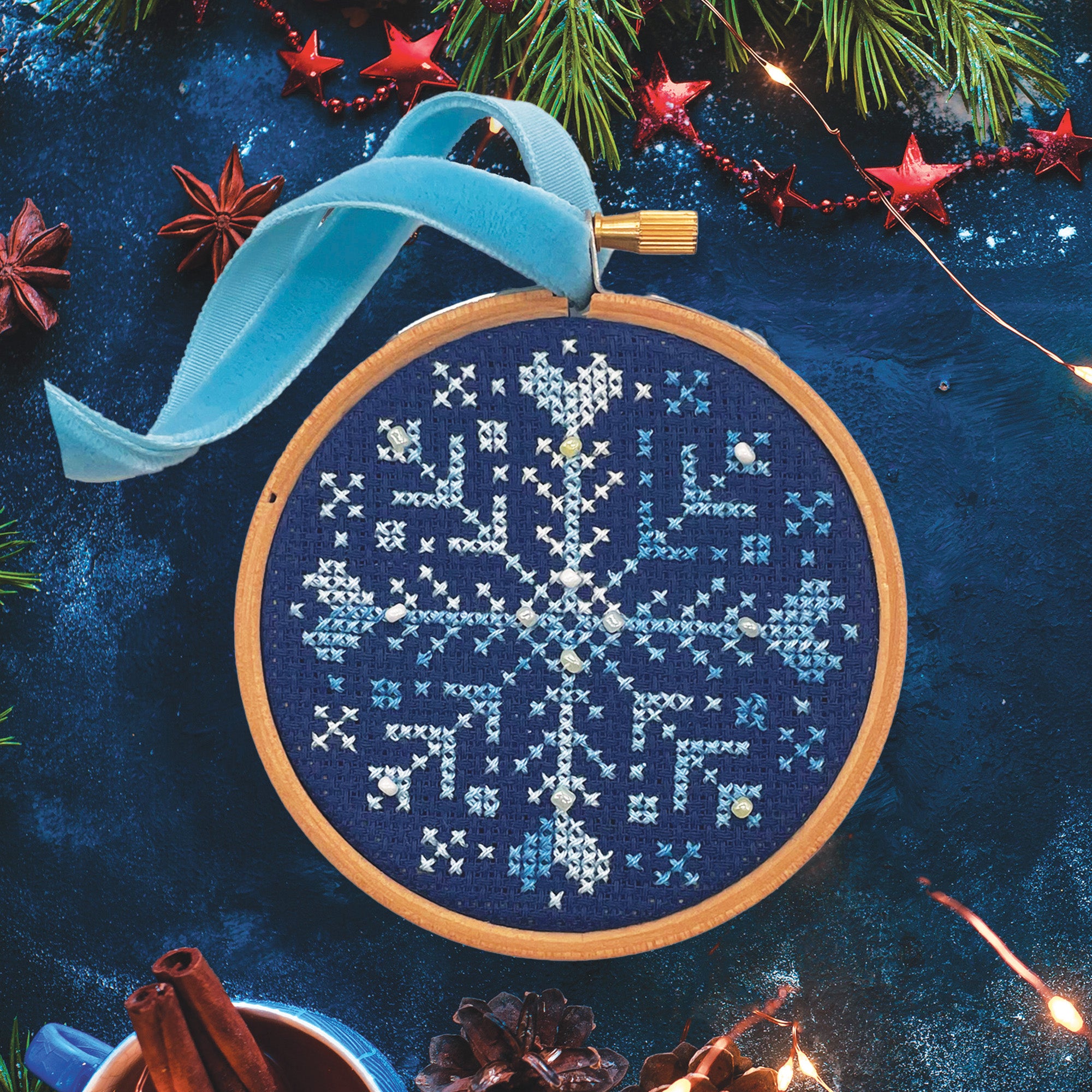 Beaded Snowflake: Christmas Cross Stitch Kit shows a detailed white snowflake embroidery in wooden hoop with festive decorations.