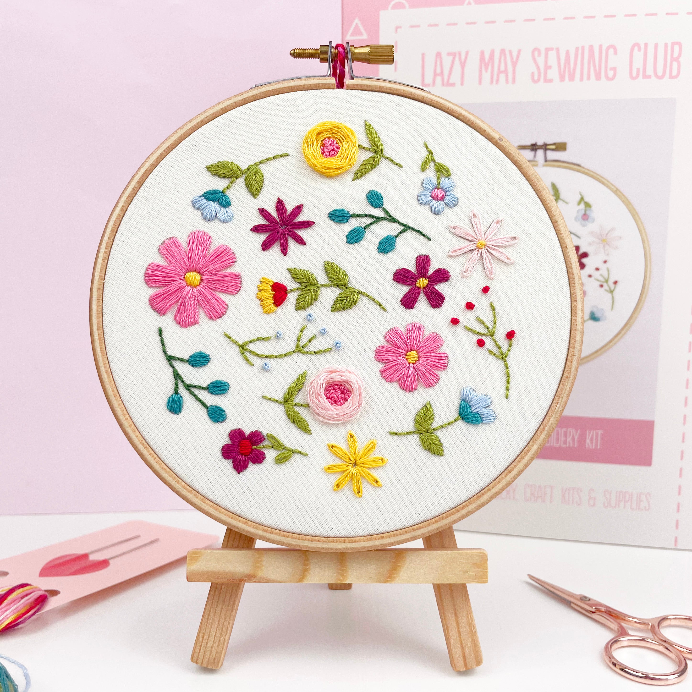 Finished wildflower embroidery hoop on wooden stand, part of a DIY floral hand embroidery kit for adults.