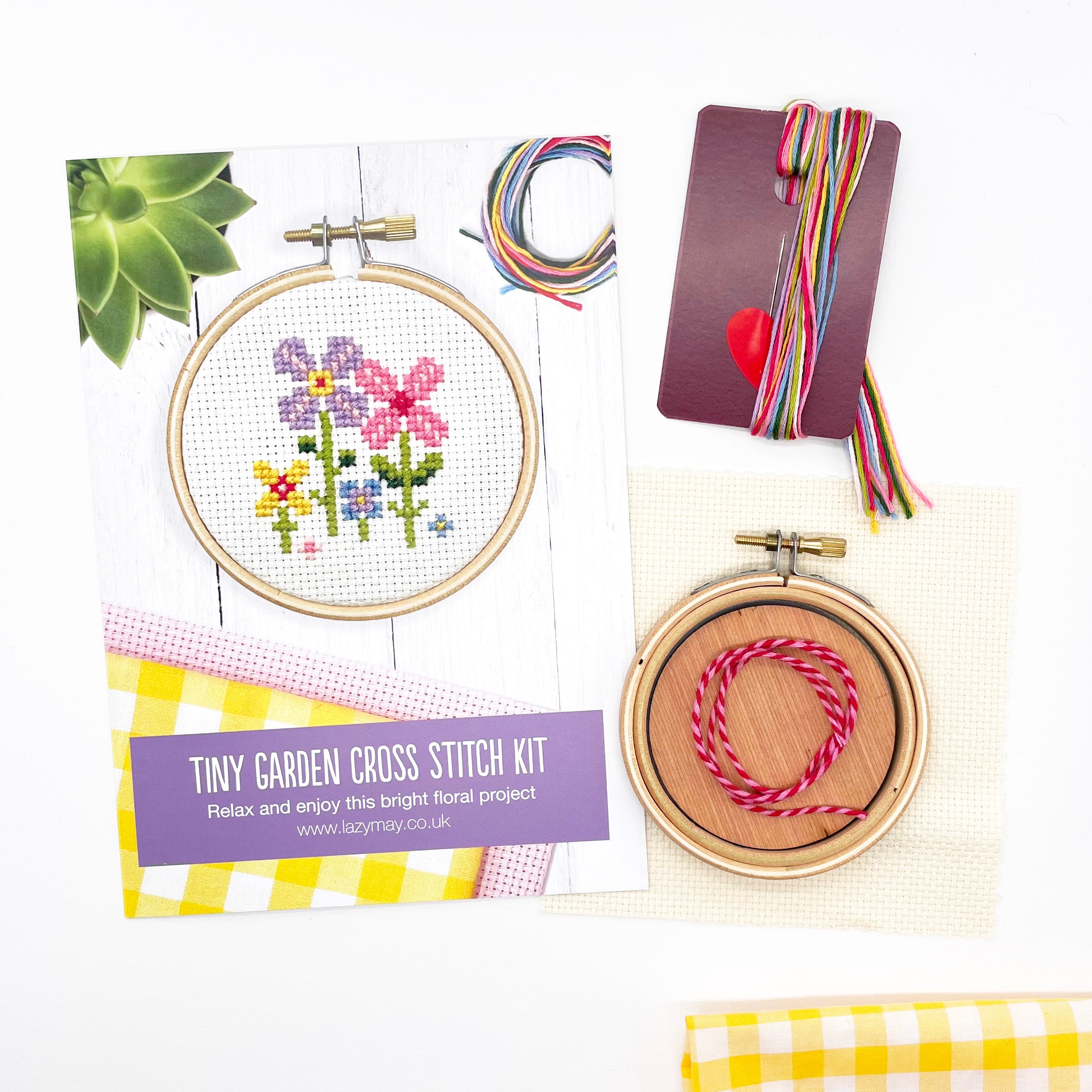 Tiny Garden: Cross Stitch Kit with floral pattern, wooden hoop, colorful threads, and fabric square for embroidery project.