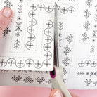 Hands cutting out a section of corner embroidery pattern from the printed Stick & Stitch sheet.
