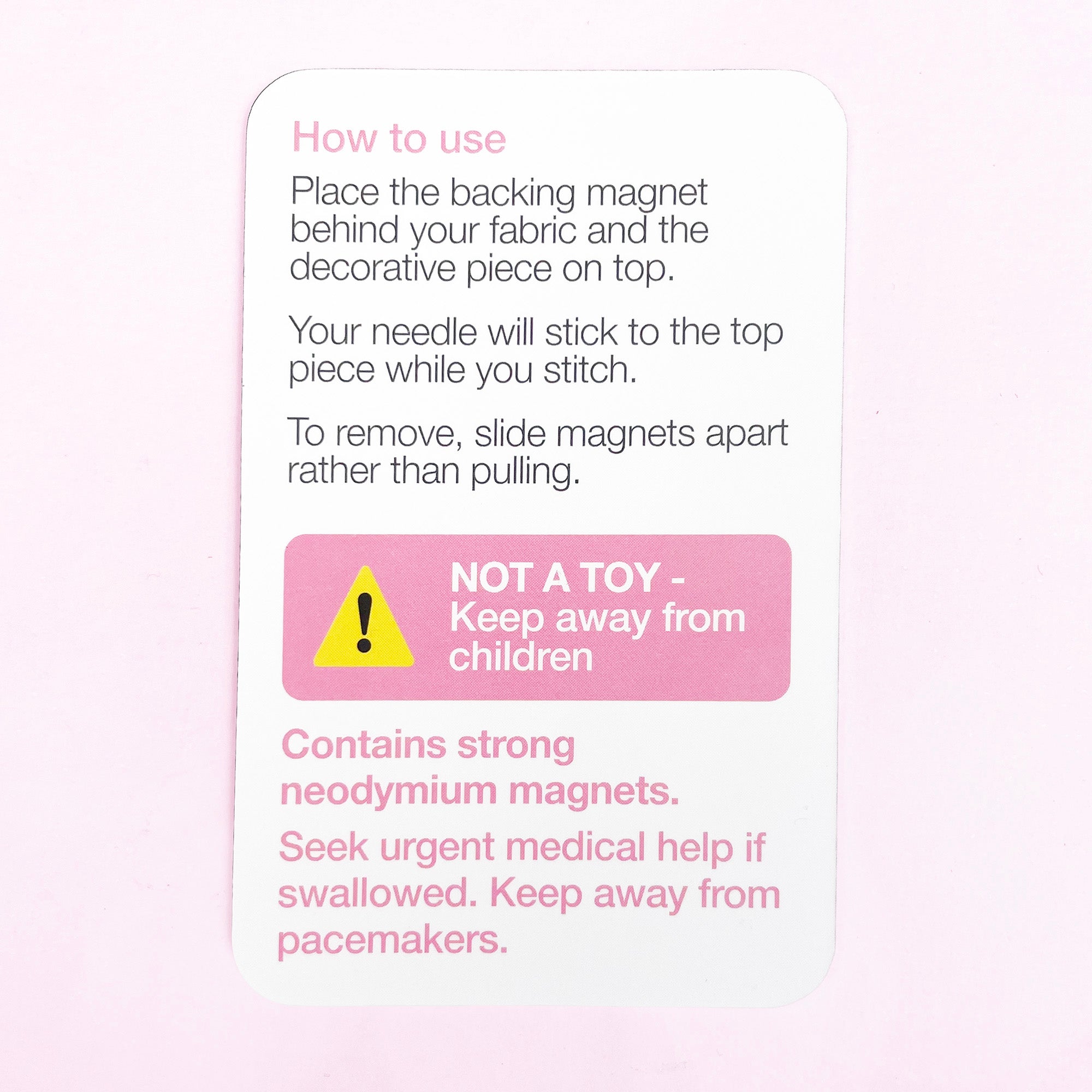 Instruction card explaining use and safety warnings for magnetic needle minder with neodymium magnets.