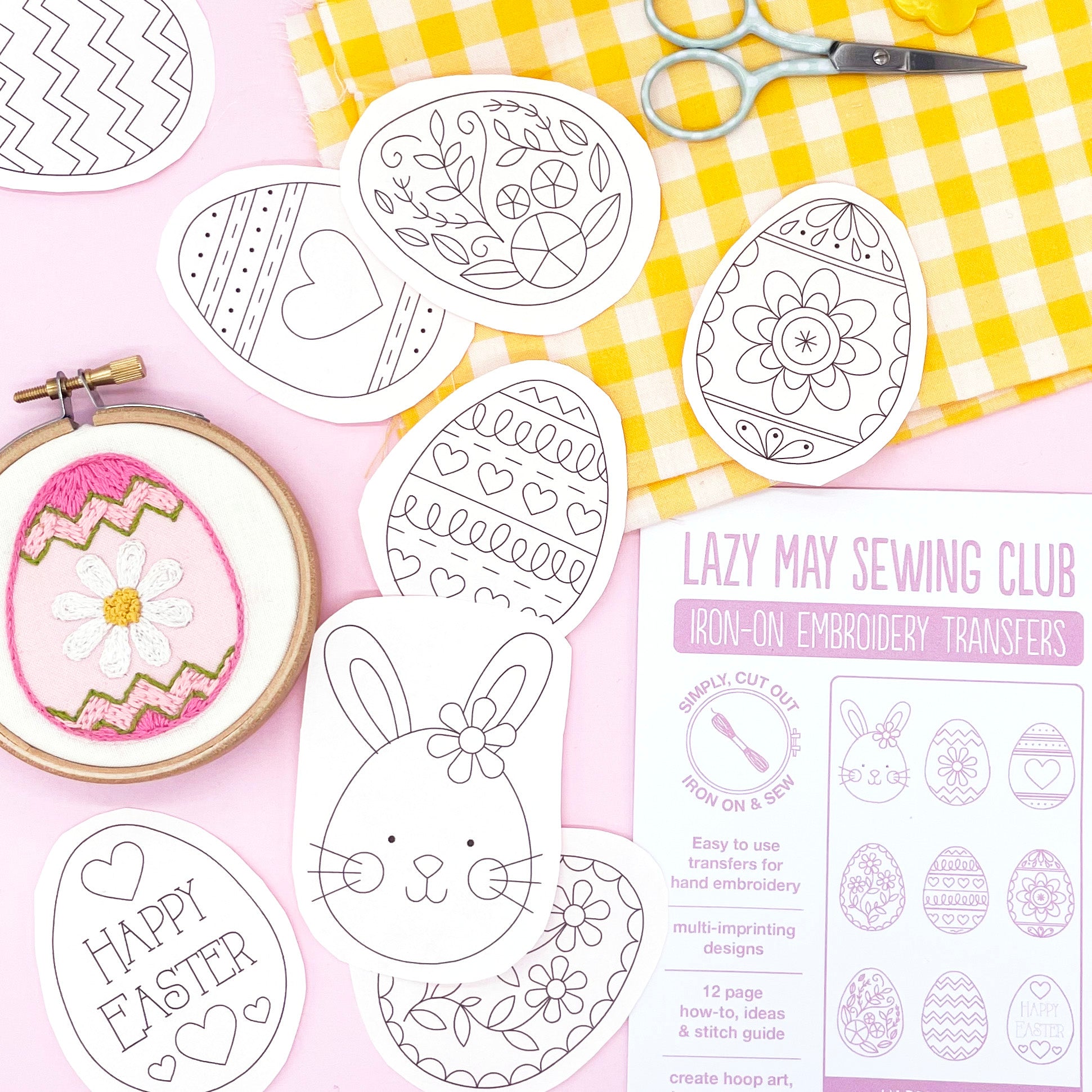 Easter embroidery patterns featuring nine iron-on transfer designs, including decorated Easter eggs and a bunny. A hoop with a stitched Easter egg design is displayed on a pink background with crafting supplies.