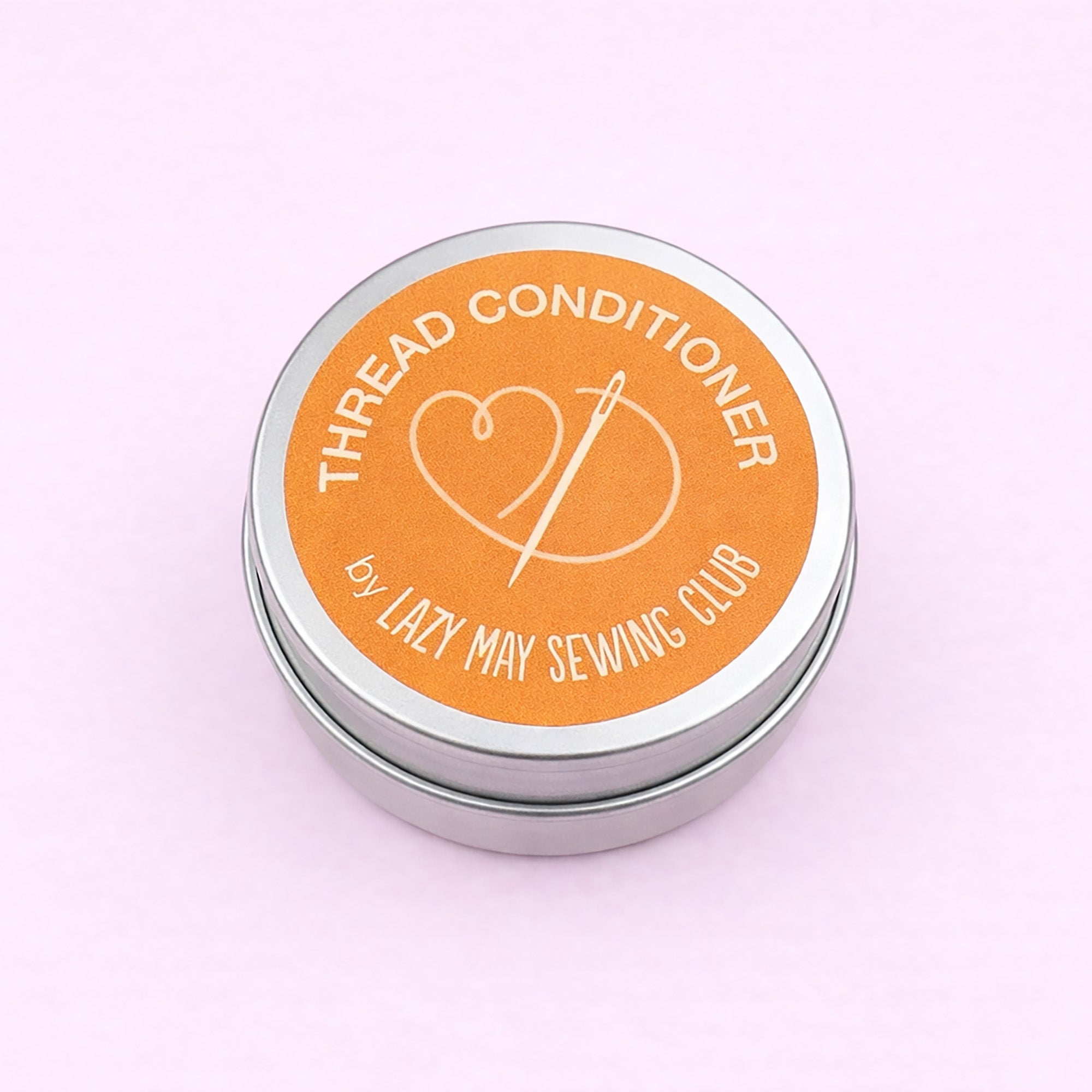 Thread conditioner container with orange label on a pink background