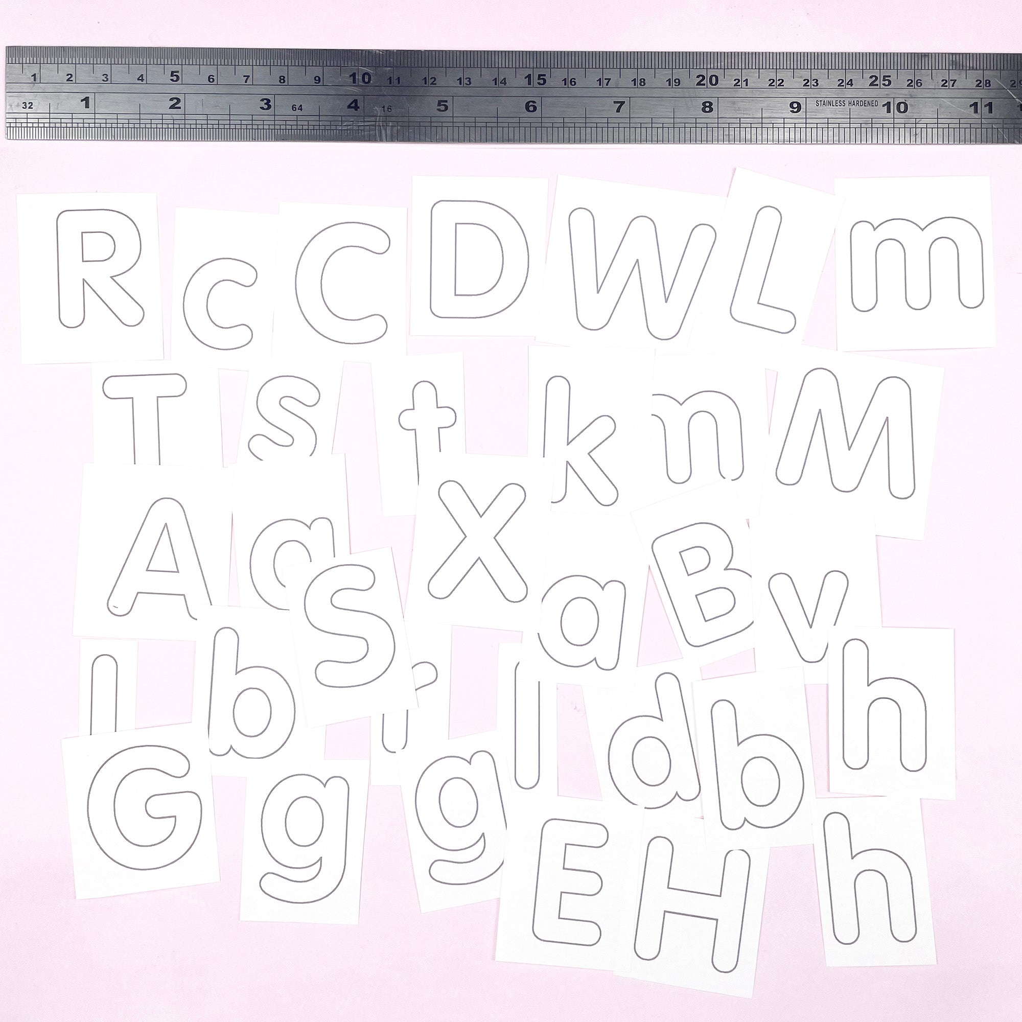 Alphabet letters embroidery patterns on paper with a ruler at the top