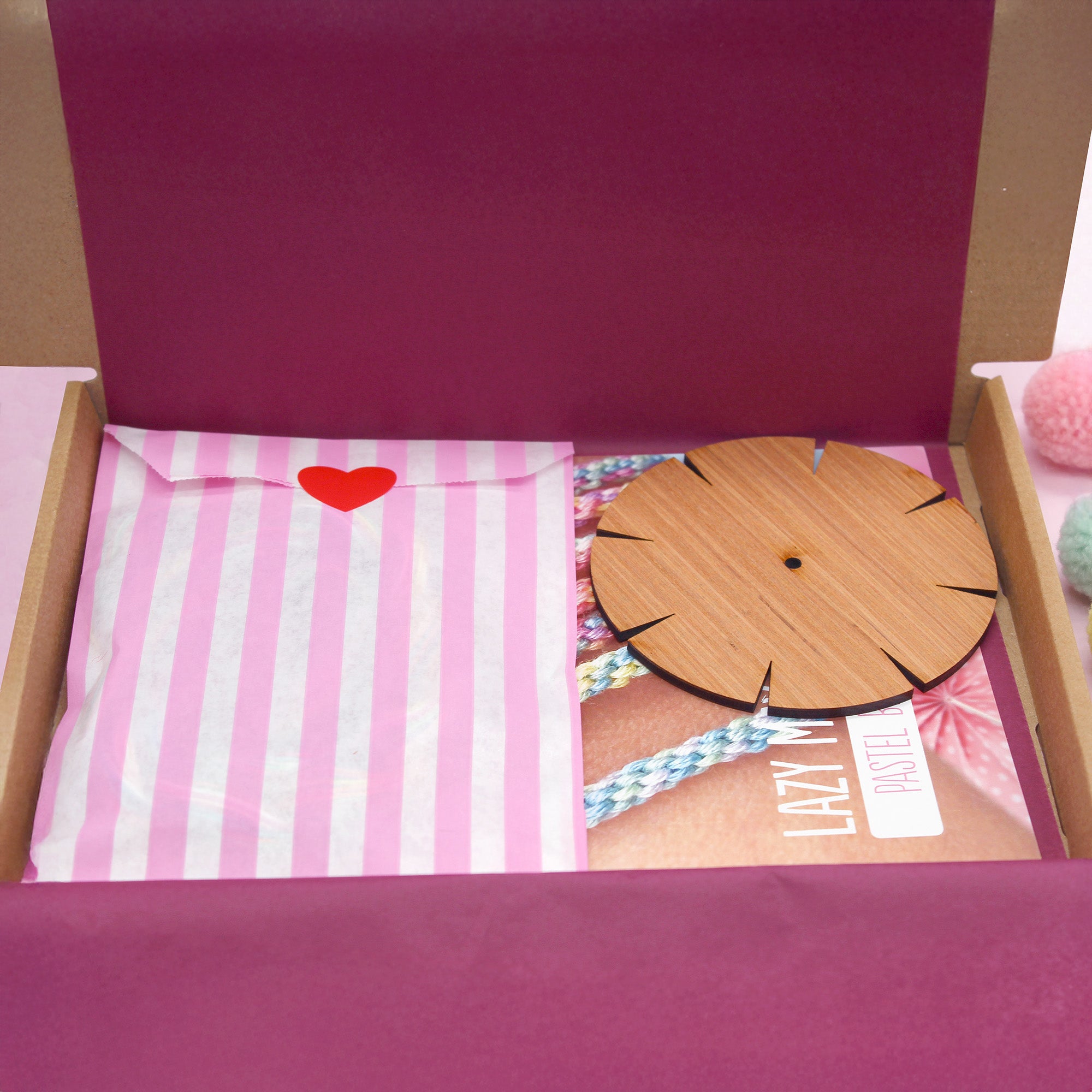 DIY bracelet kit open box showing striped tissue paper, kumihimo loom, threads and instructions – ideal craft party or stocking filler.