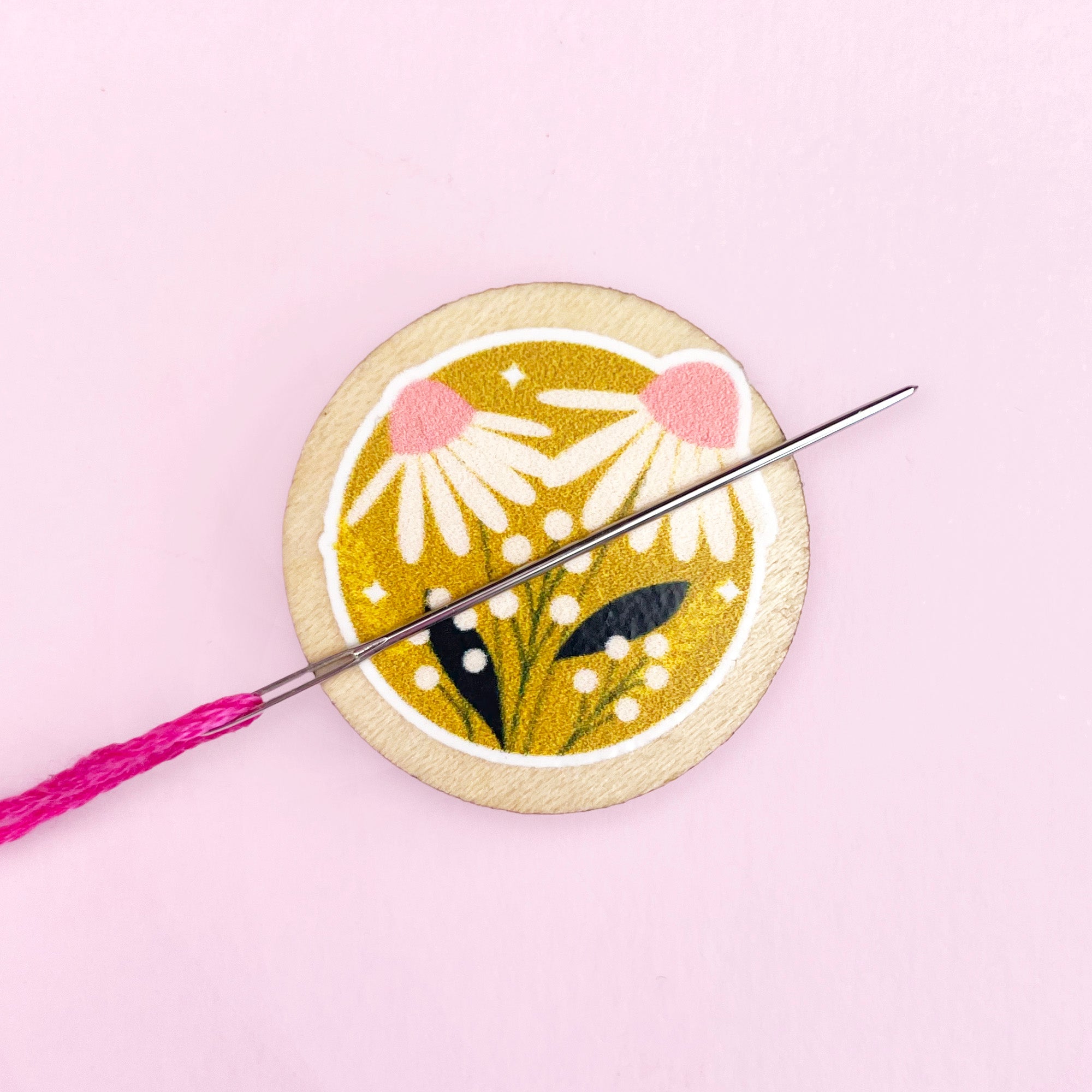 Embroidery needle minder with floral design and pink thread on a light pink background
