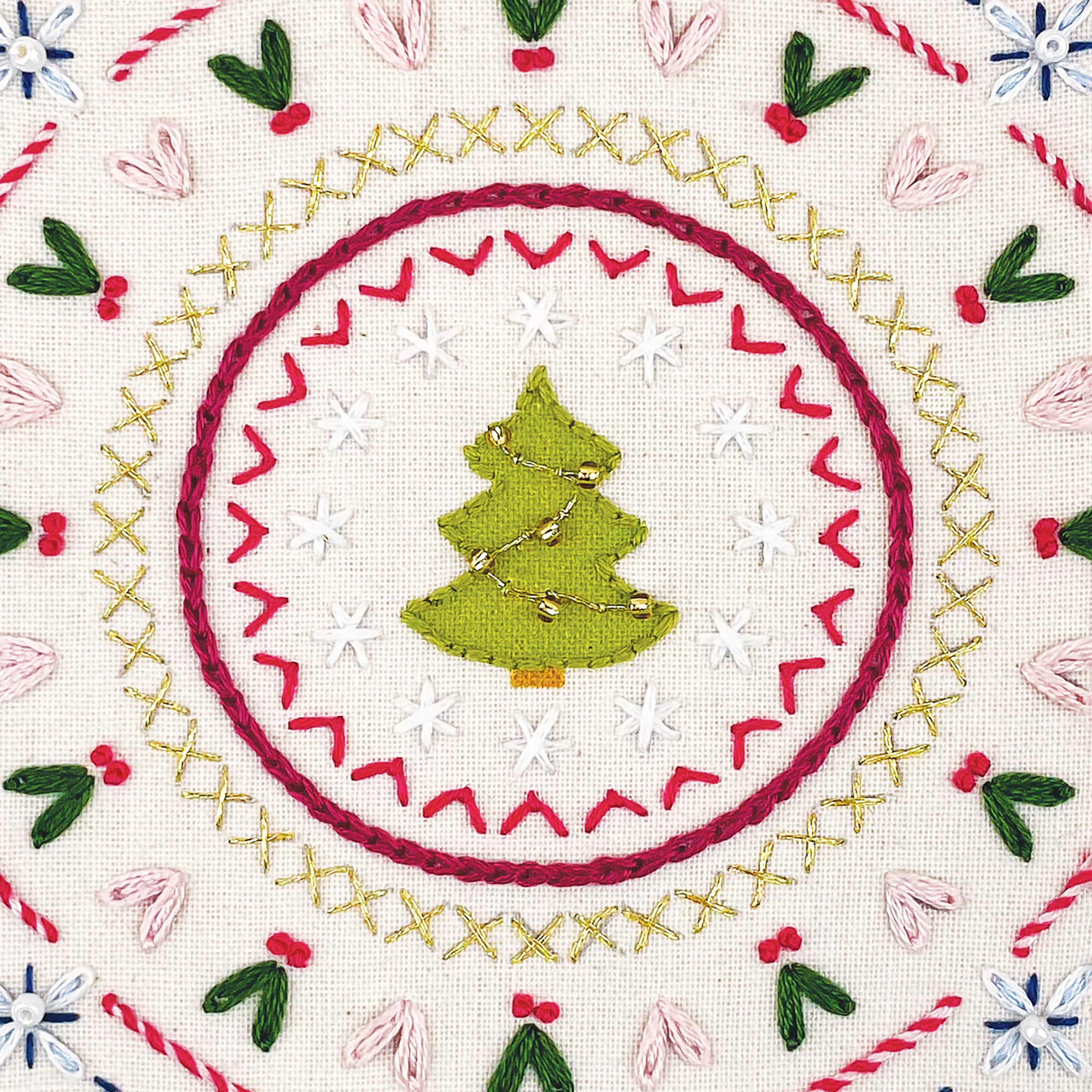 Embroidered design of a Christmas tree surrounded by festive patterns on a white background.