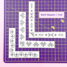 Corner embroidery patterns laid out on a purple cutting mat showing scale, with a 1cm grid.