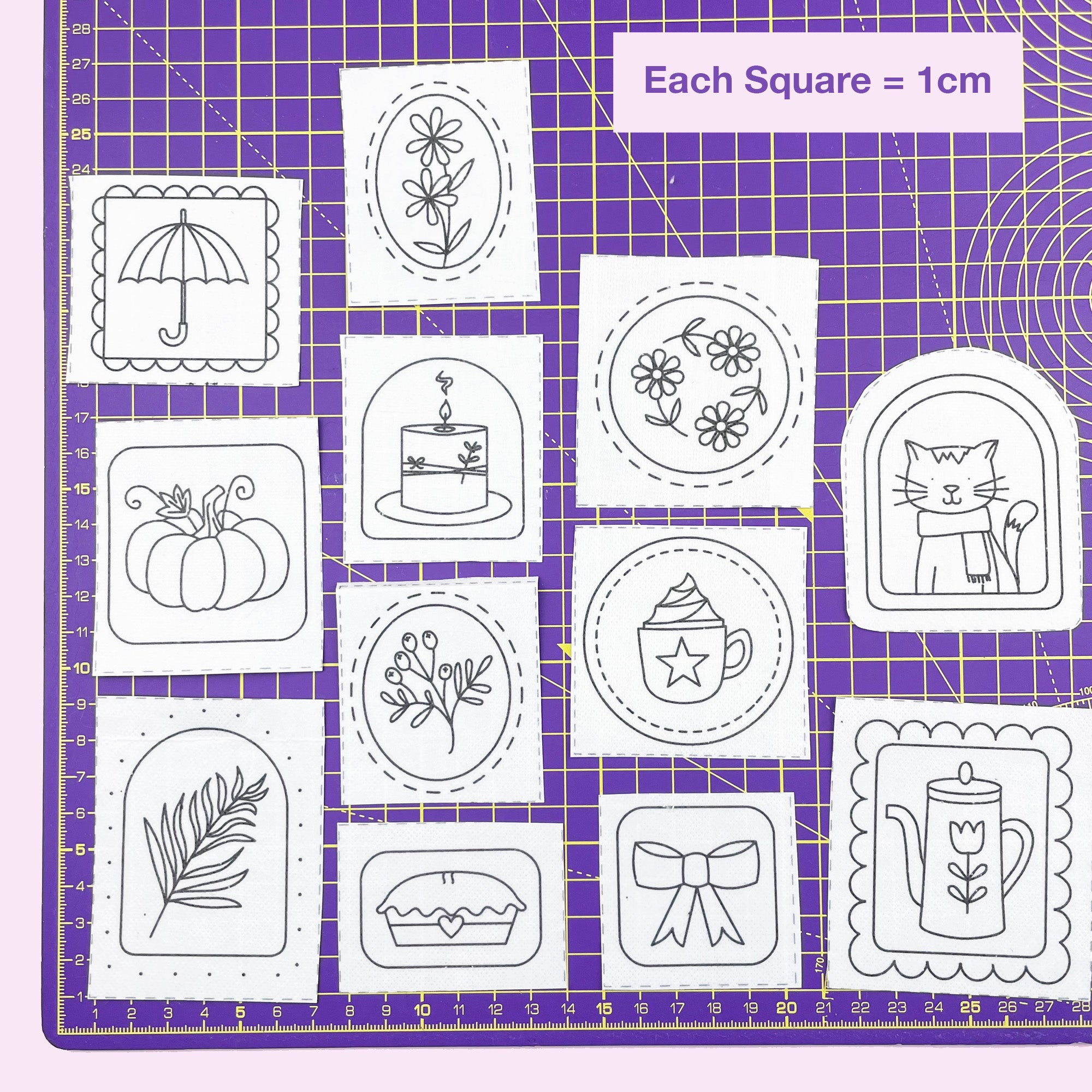 Black and white embroidery pattern sketches on a purple grid mat for Autumn Doodles: Stick and Stitch Embroidery Patterns