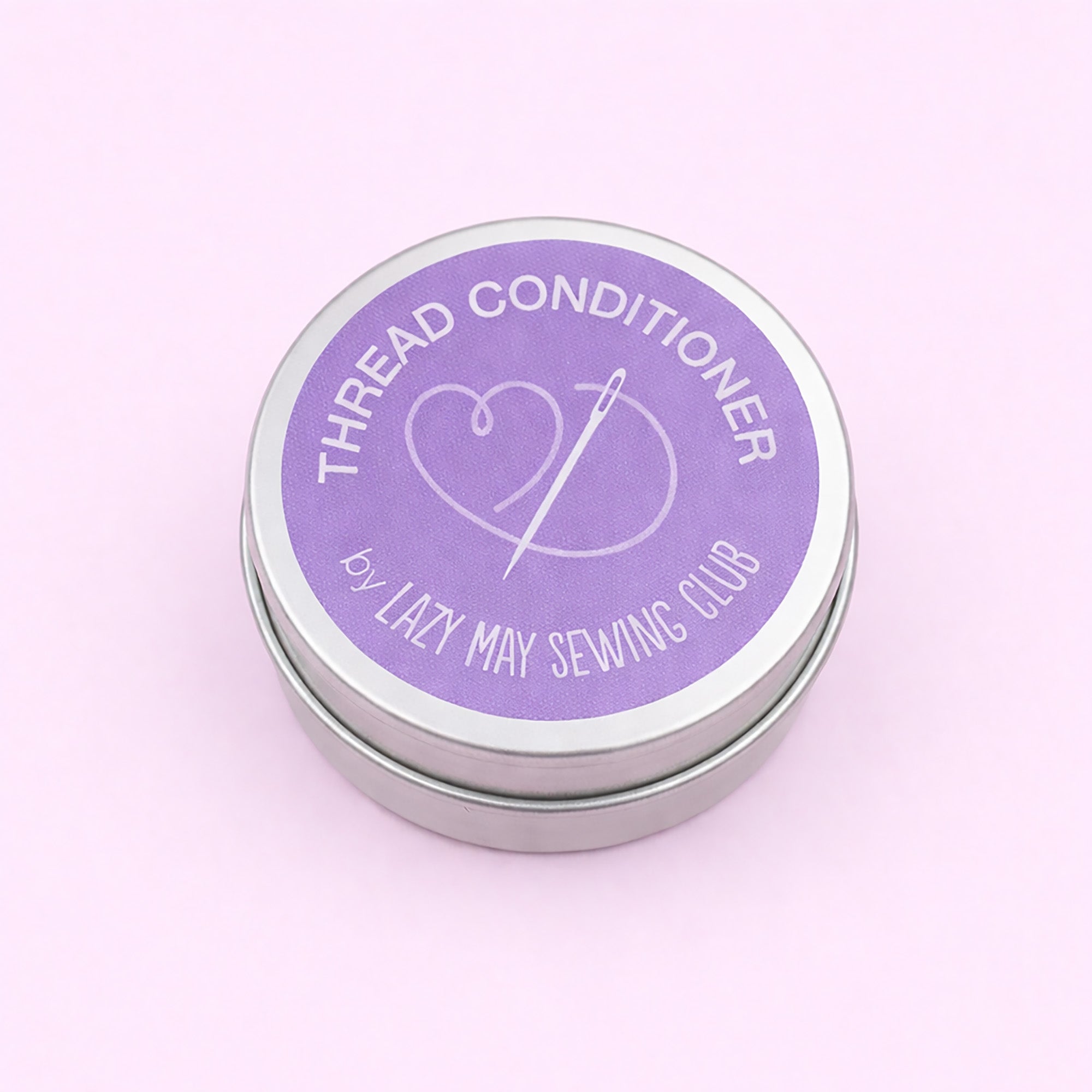 floral Thread conditioner tin with purple label on a light pink background