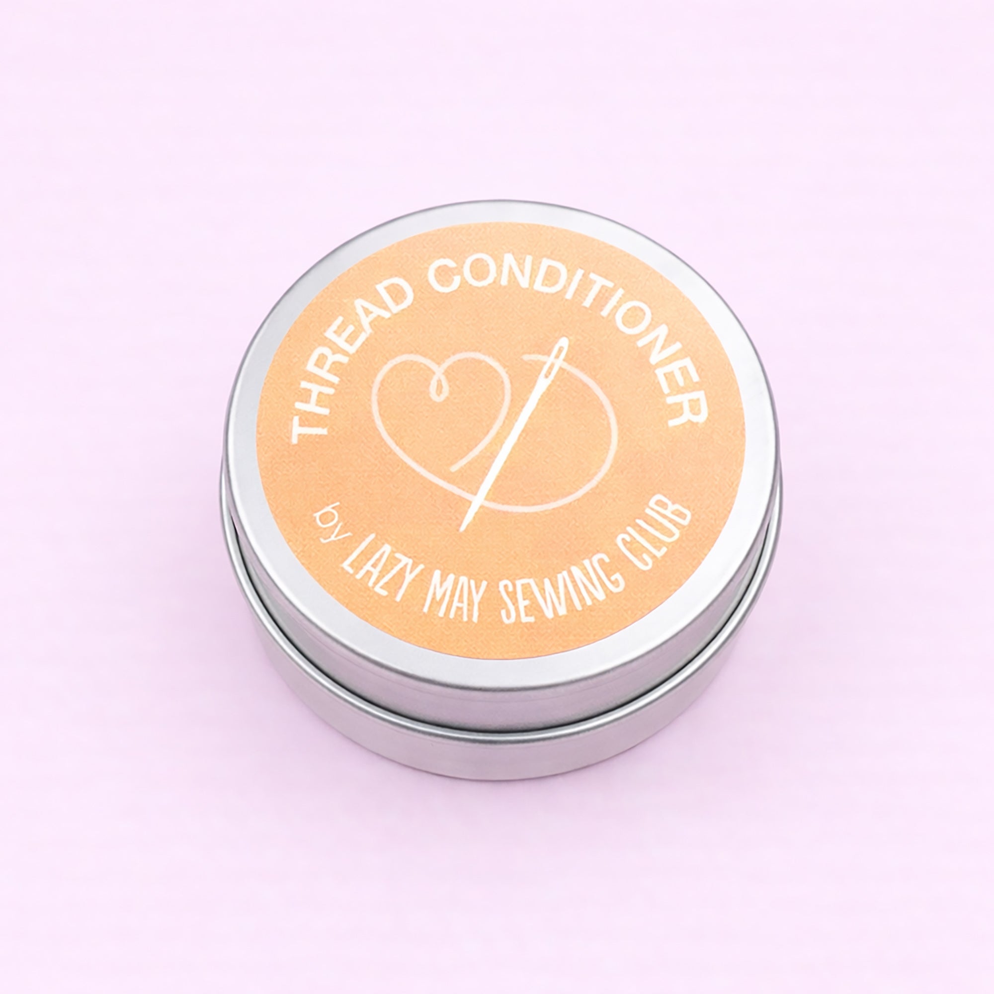 Thread conditioner container with 'Lazy May Sewing Club' branding on a light pink background
