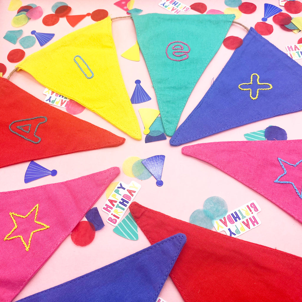 Handstitched personalised party bunting stitched with iron on embroidery patterns alphabet design the word Alex is spelt out on colourful flags