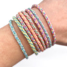 Close-up of finished kumihimo bracelets worn on the wrist, made using the Lazy May handmade bracelet kit – soft pastel tones.