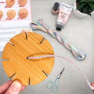 Close-up of kumihimo bracelet being woven on a wooden loom from the woven bracelet kit – shows pastel threads and simple setup.