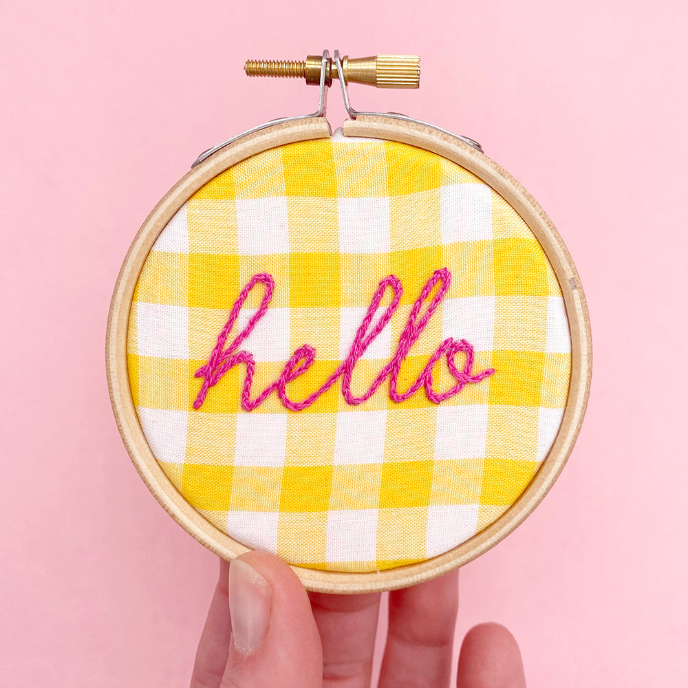 gingham embroidery hoop with the word hello stitched on it