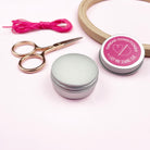 Sewing kit with scissors, thread, and a container labeled 'Thread Conditioner' on a light pink background.