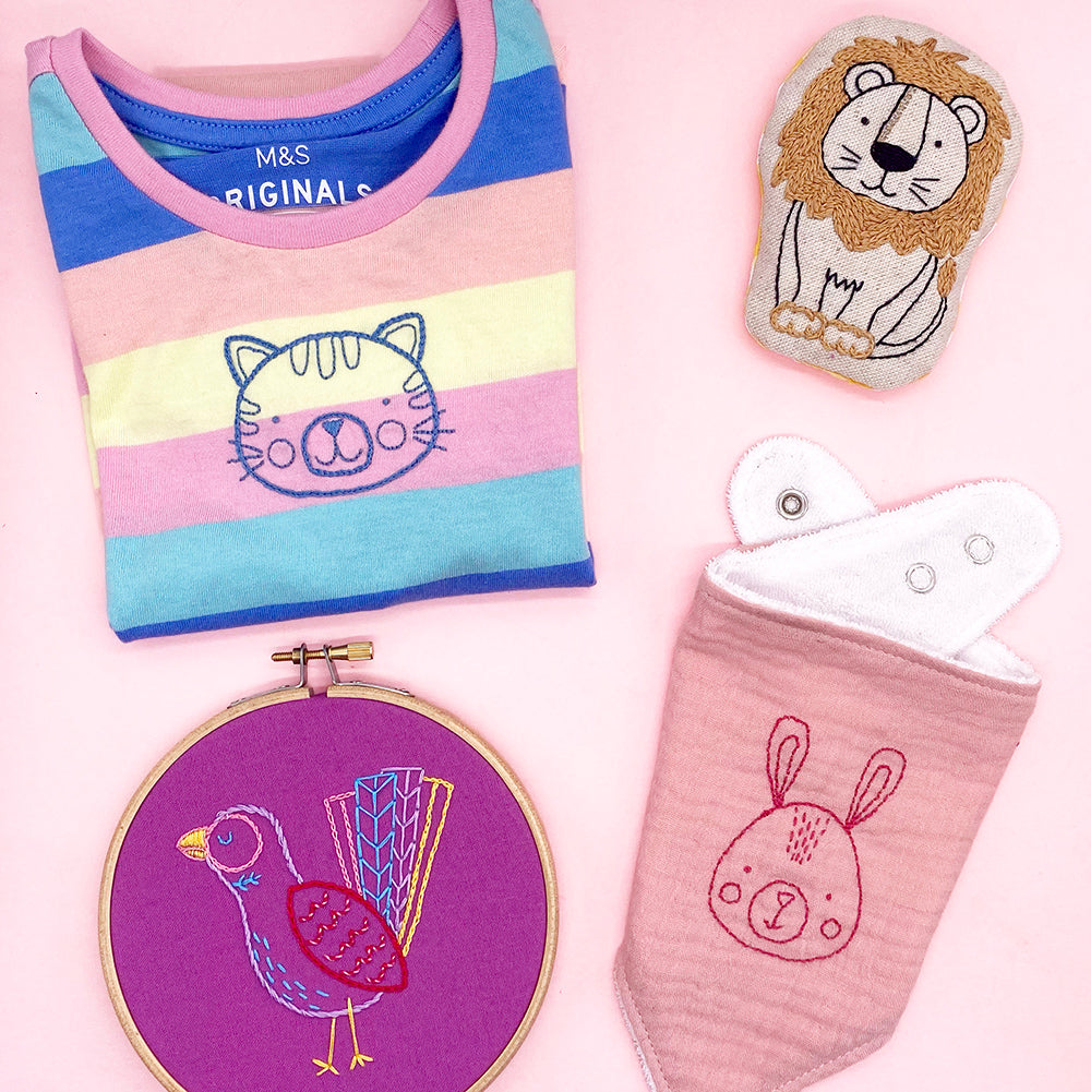 Friendly face animal iron-on embroidery patterns stitched onto a children’s t-shirt, baby items and hoop art
