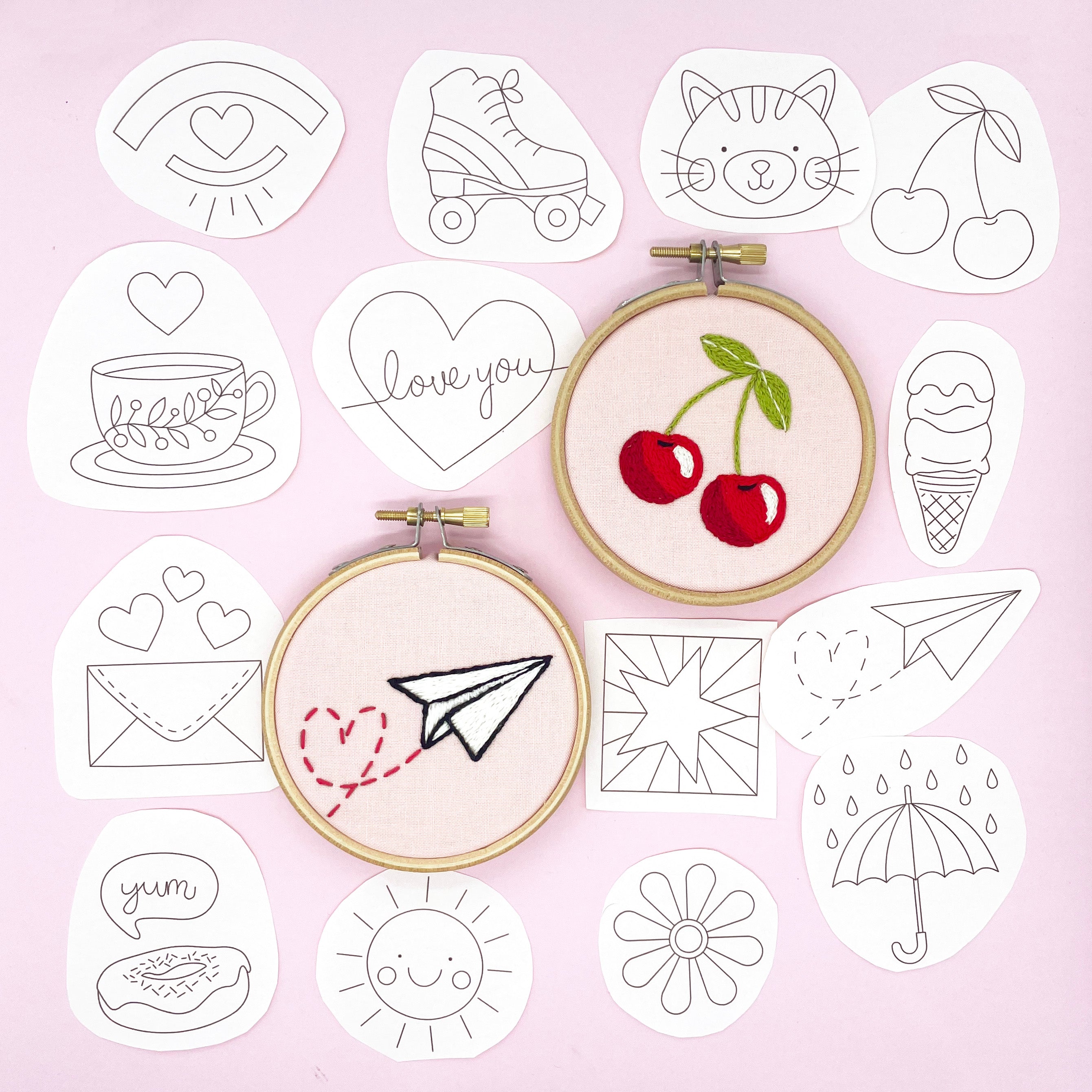 Doodles iron-on embroidery patterns featuring a collection of fun designs, including cherries, a paper plane, and a teacup. Two completed embroidery hoop designs are displayed, perfect for Easter embroidery patterns and Easter crafts.