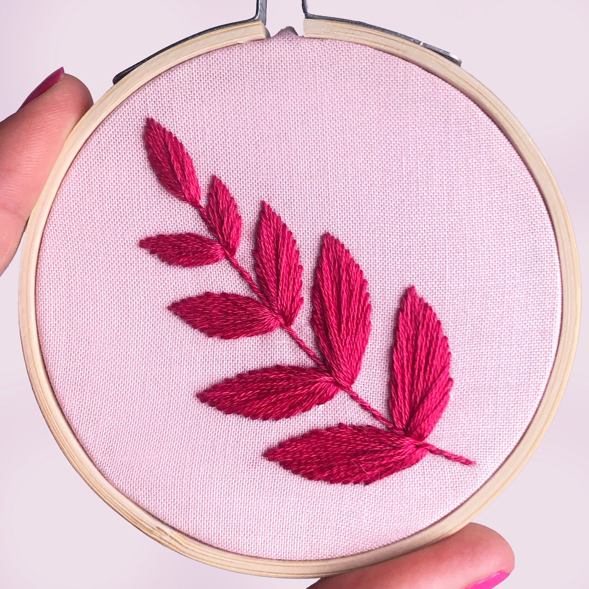 Embroidery hoop with red leaf design on pink fabric