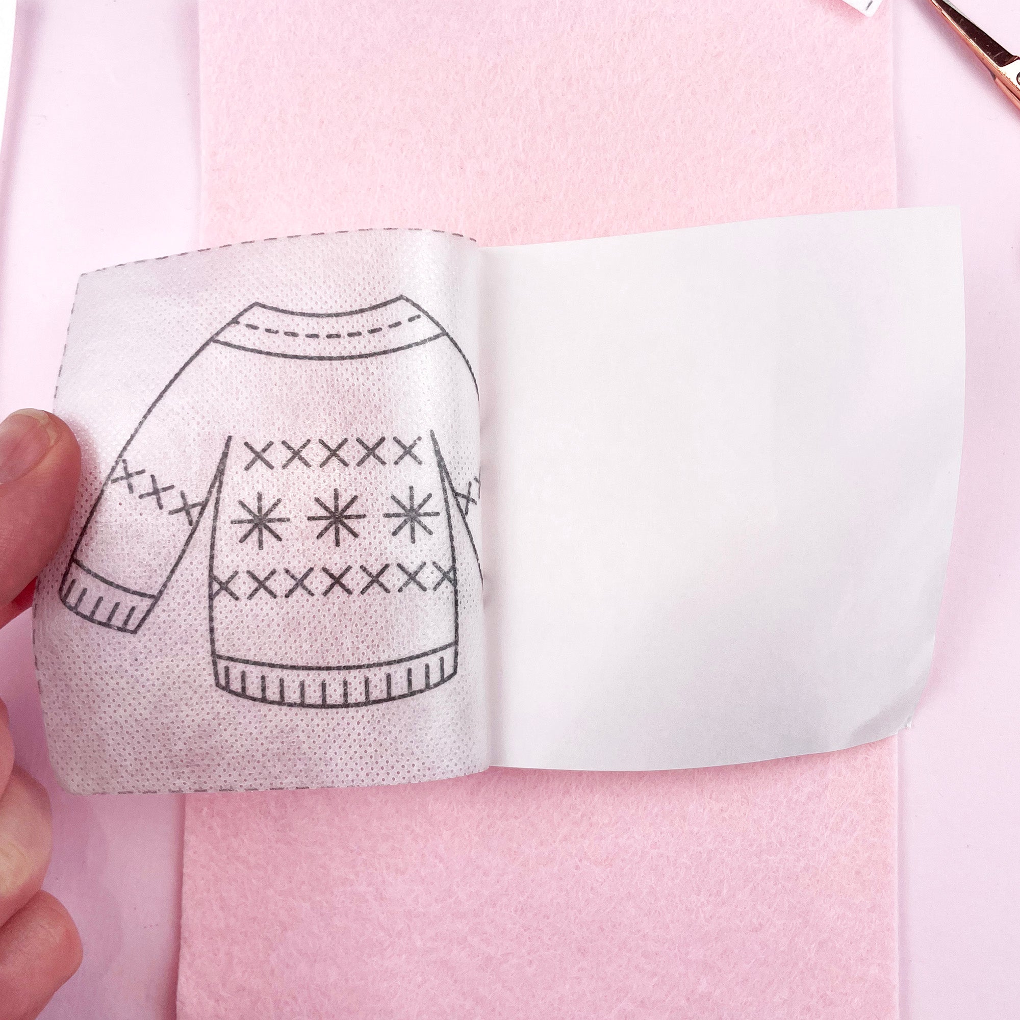 Embroidery pattern of a sweater held over pink fabric