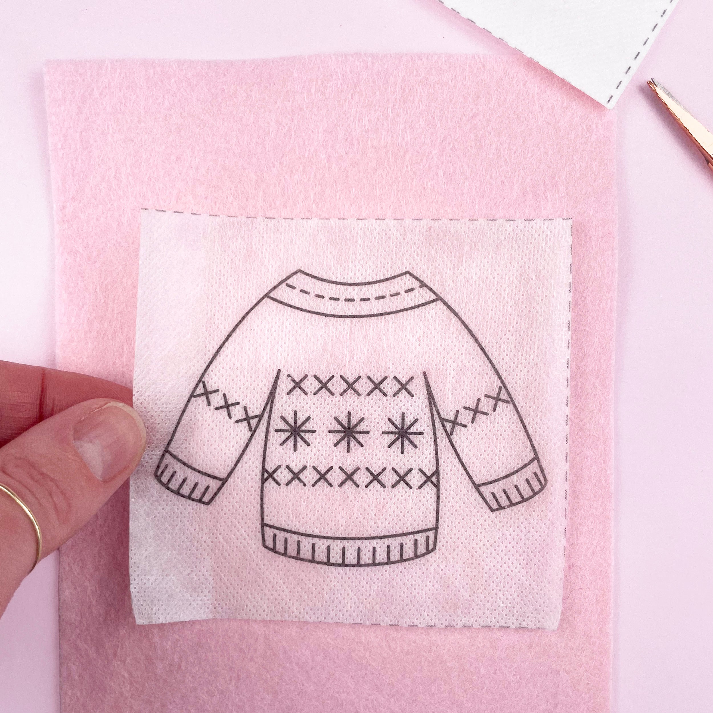 Embroidered sweater design on a pink fabric background