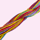 Brightly colored embroidery threads twisted together against a soft pink background for beginner kits.