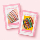 Two pink boxes for a 'Lazy May Sewing Club' friendship bracelet weaving kit, shown on a light pink background. The boxes feature photos of colorful woven bracelets and text indicating they contain modern embroidery craft kits and supplies.