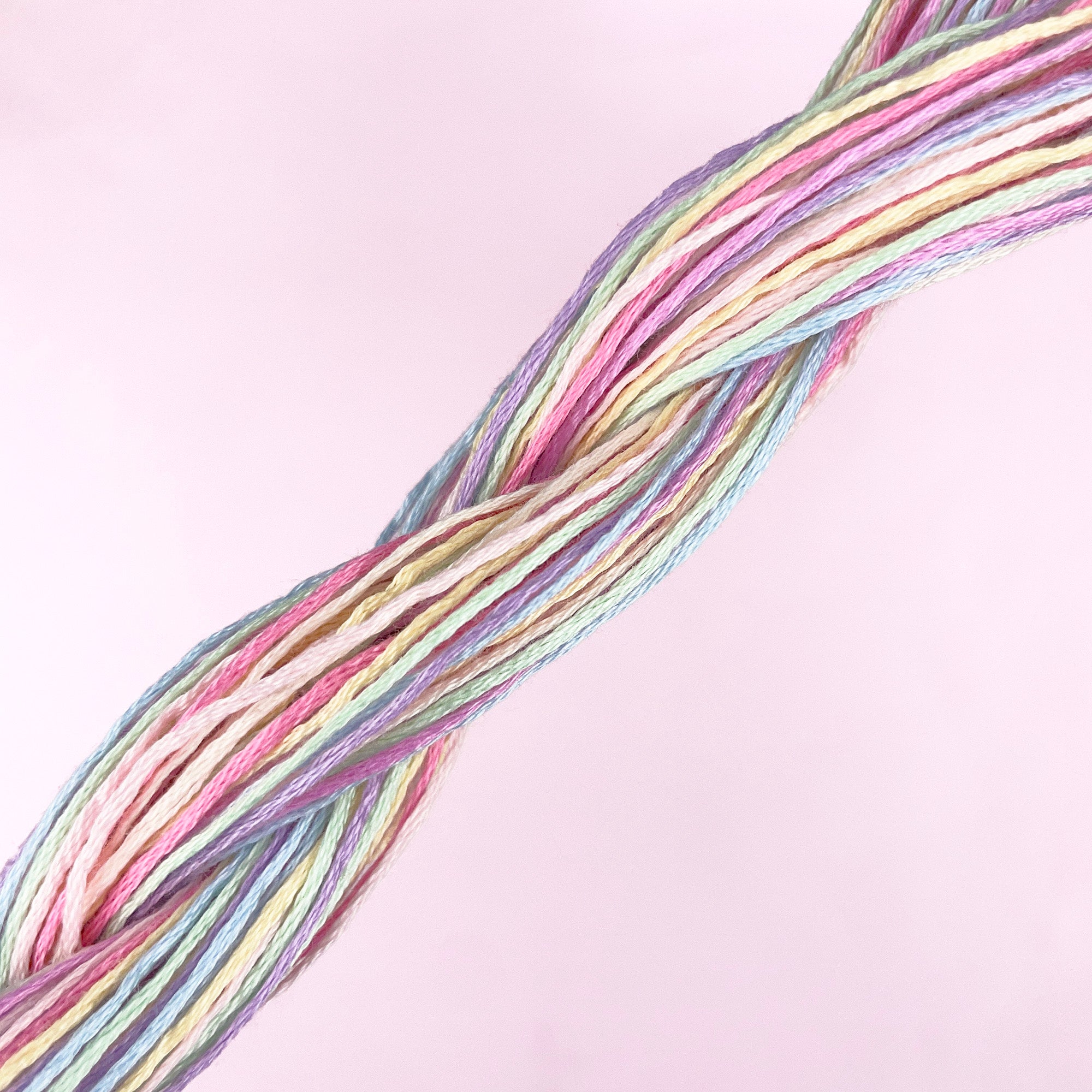 Pastel-colored embroidery threads twisted together against a soft pink background for easy embroidery projects