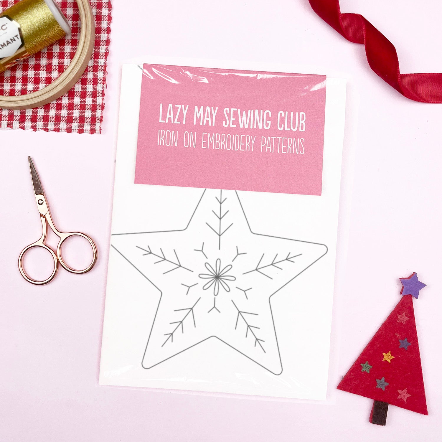 A flat-lay of an iron-on embroidery pattern sheet from Lazy May Sewing Club, featuring a star-shaped outline. The sheet has a pink header label and is wrapped in clear plastic.