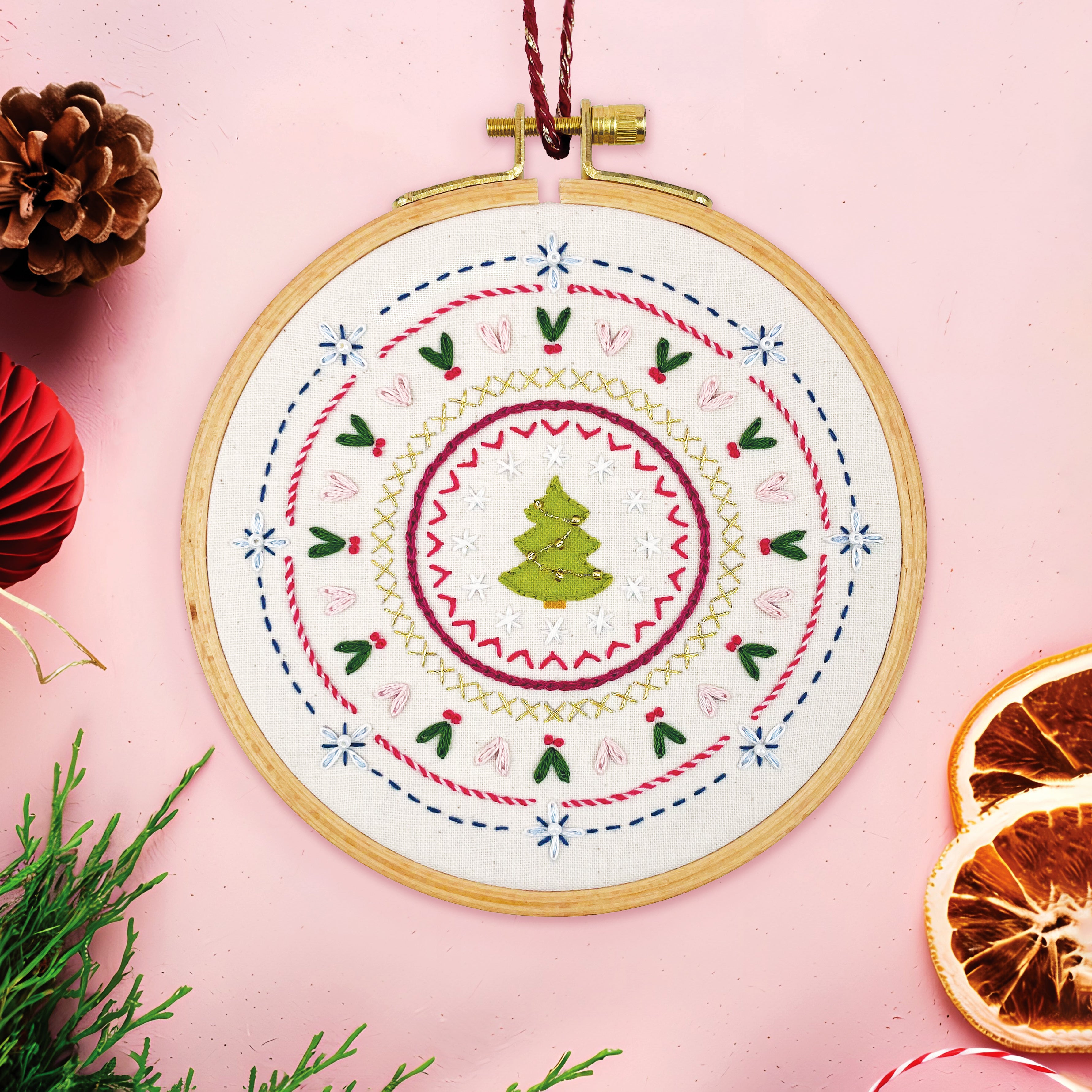 Embroidery hoop with Christmas-themed design on a pink background