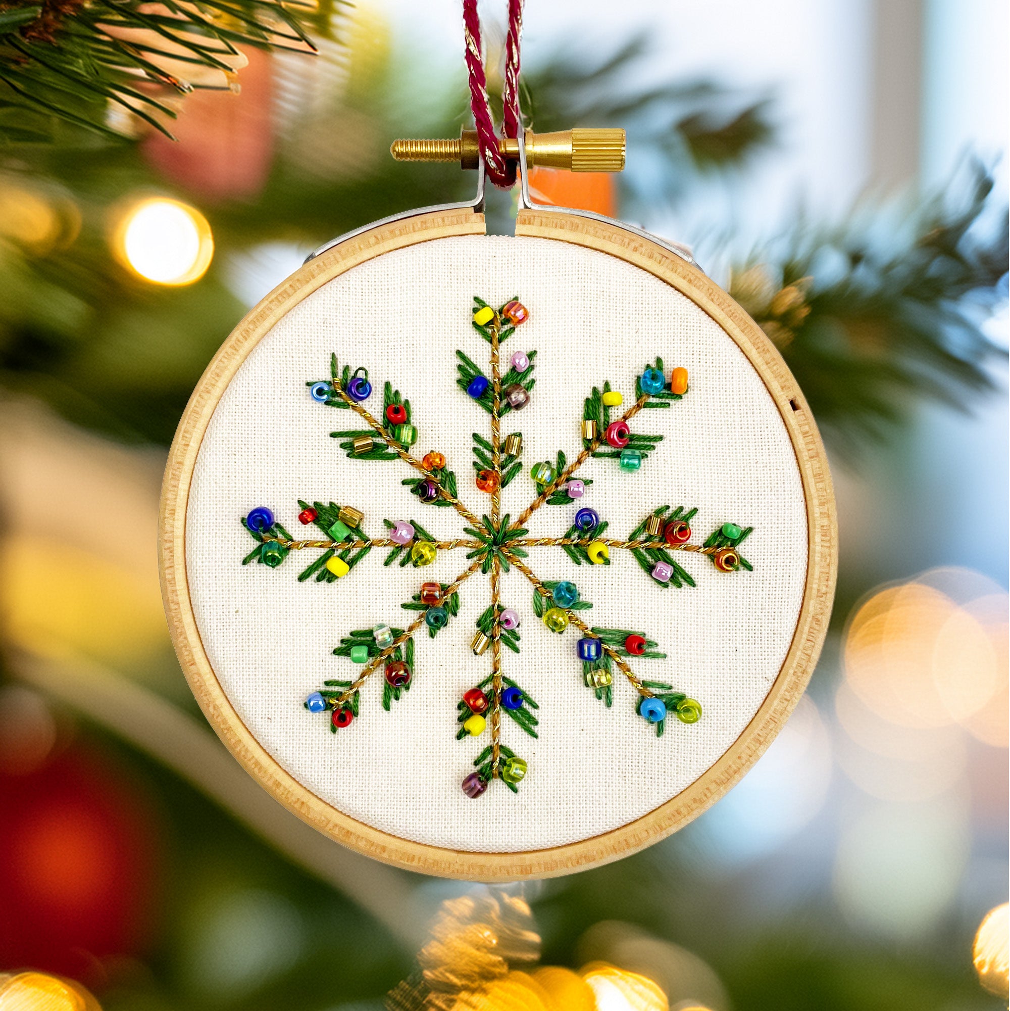 Embroidered snowflake ornament on a Christmas tree with blurred lights in the background