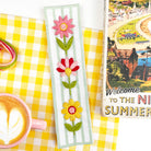 Finished floral embroidery bookmark with pink, red and yellow flowers, styled with coffee and thread. Easy bookmark kit for beginners.