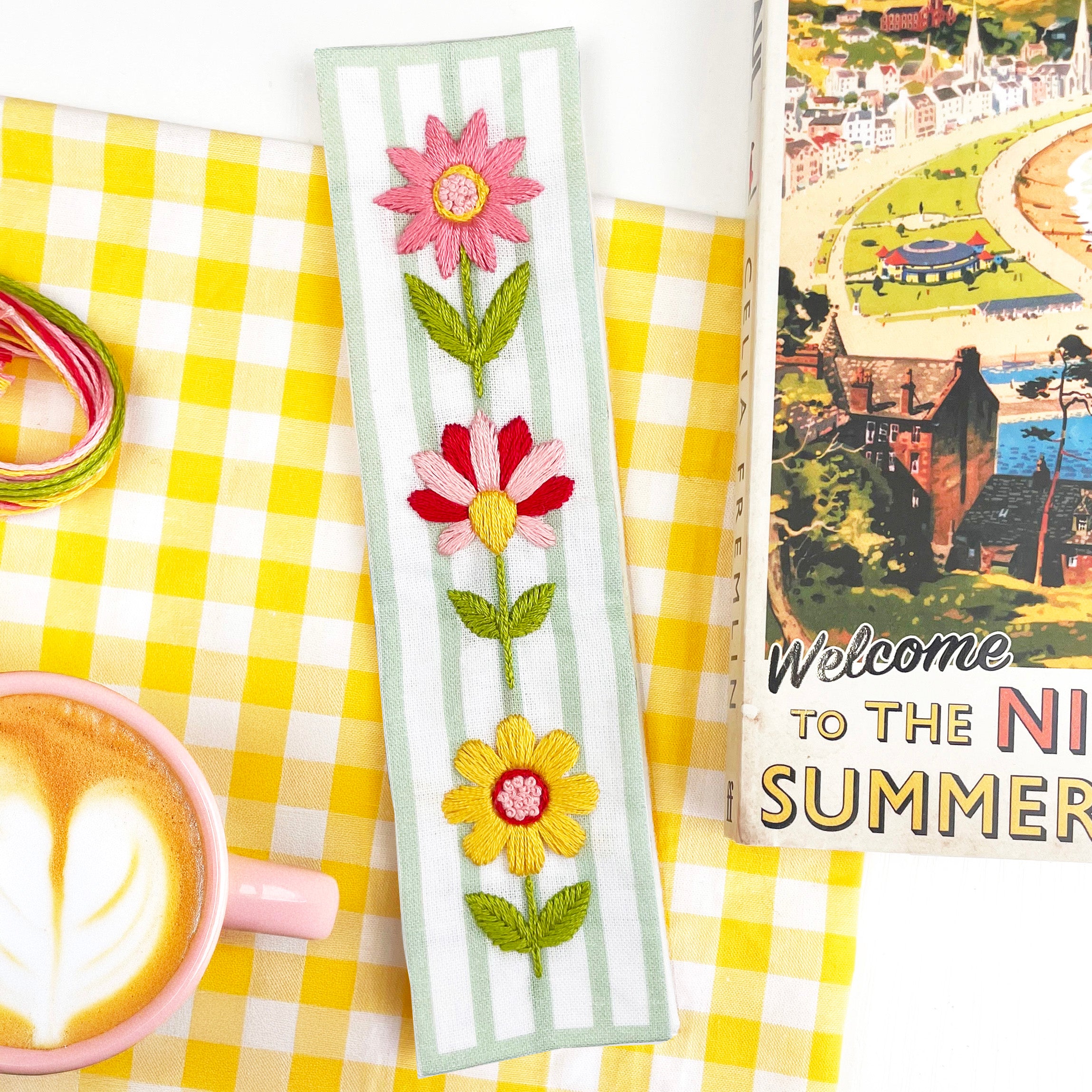 Finished floral embroidery bookmark with pink, red and yellow flowers, styled with coffee and thread. Easy bookmark kit for beginners.