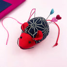 Cute red and navy mouse pin cushion made from cotton, holding sewing pins with heart-shaped heads.
