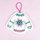 Decorative patch of a knitted sweater with a snowflake design on a pink background